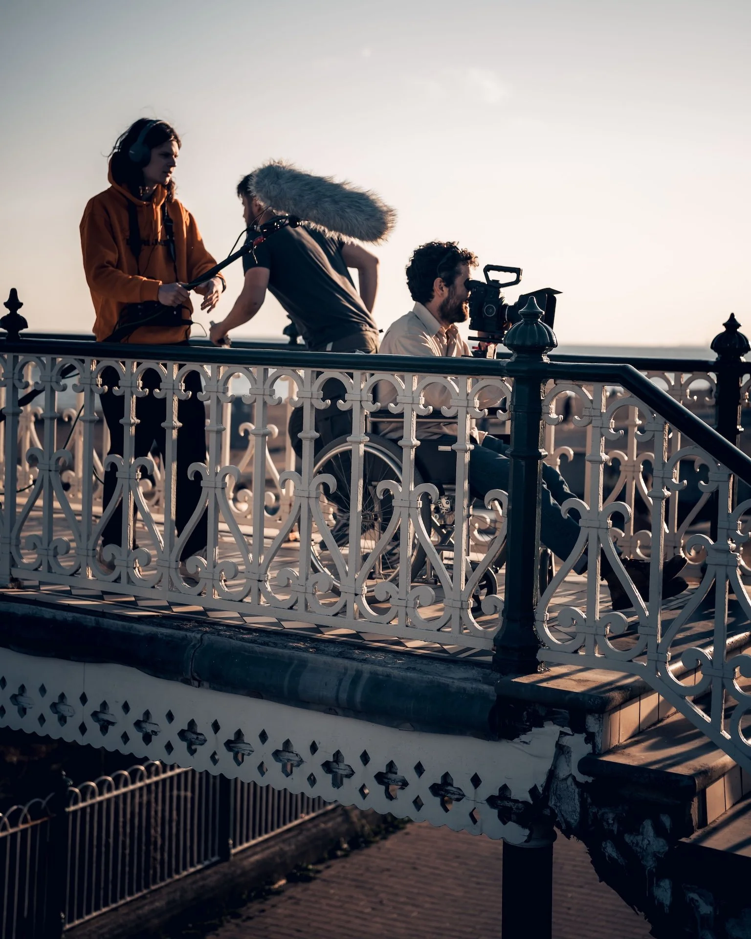 Filming crew setting up equipment on an ornate outdoor balcony during sunset.