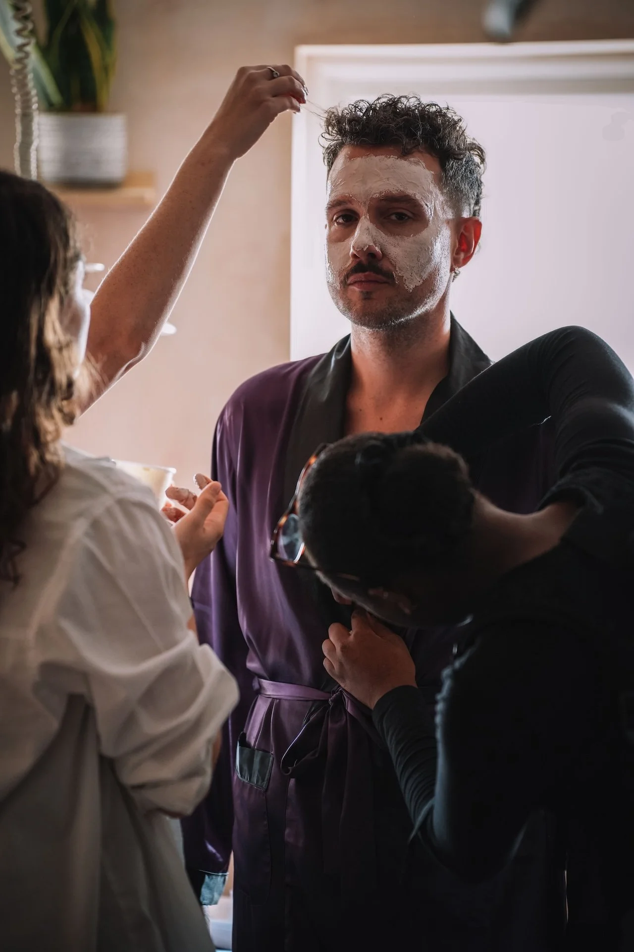 A man with a facial mask applies face mask to another person's face in a salon.