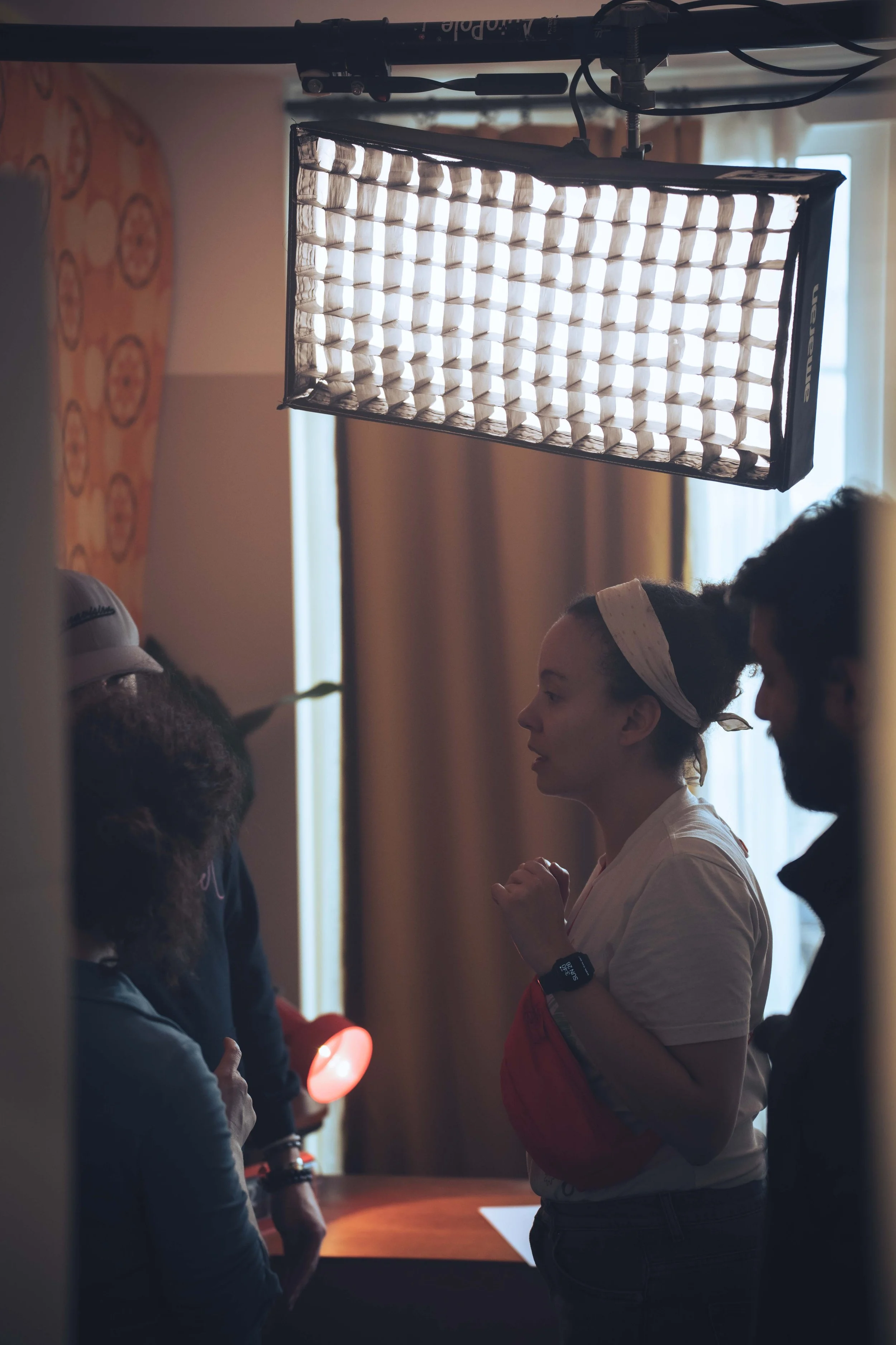A group of people standing in a dimly lit room with curtains and windows, with one person holding a lighted object.