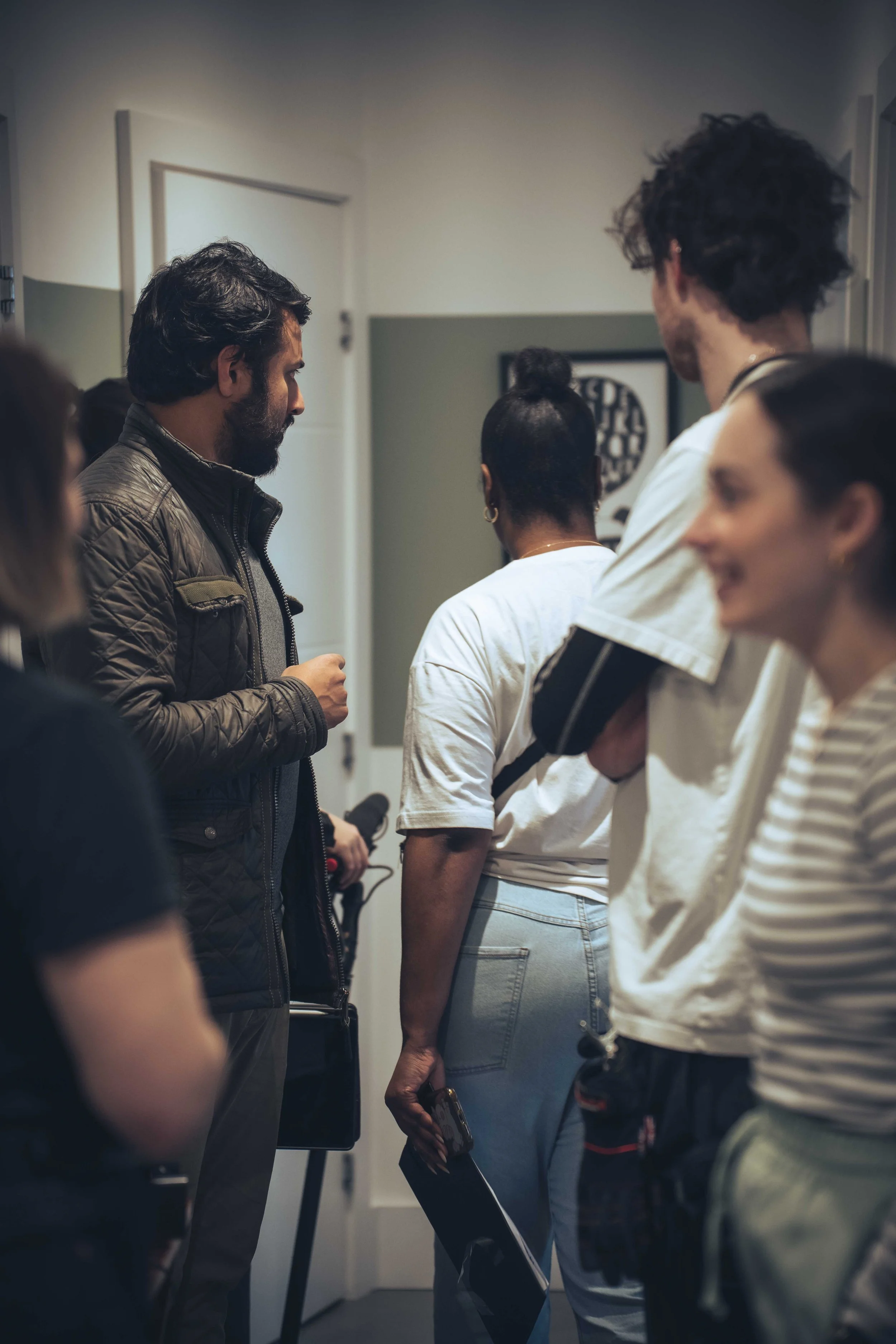 Group of people standing in a hallway, engaging in conversation.