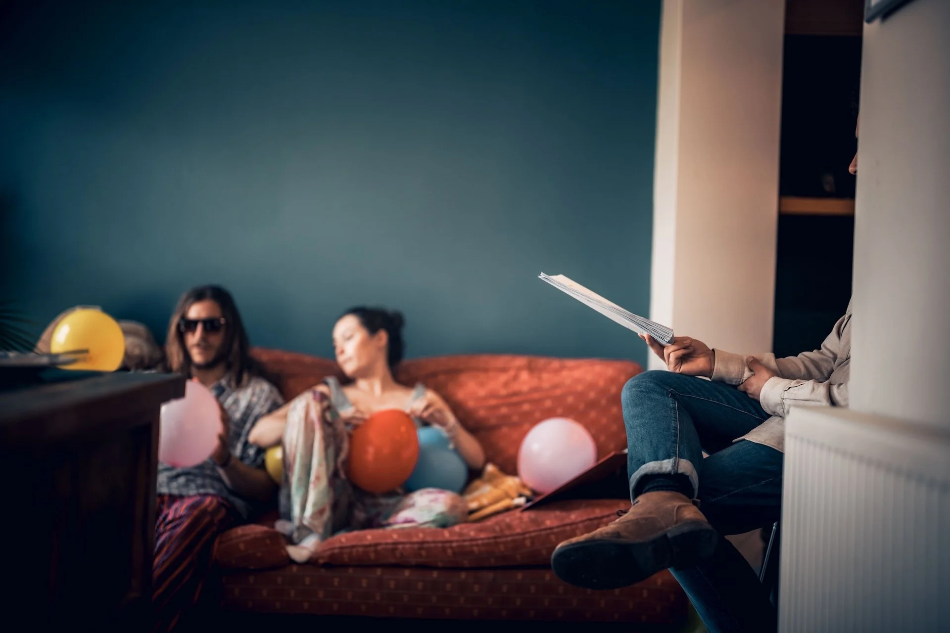 People celebrating at a gathering with balloons and party decorations in a cozy living room.