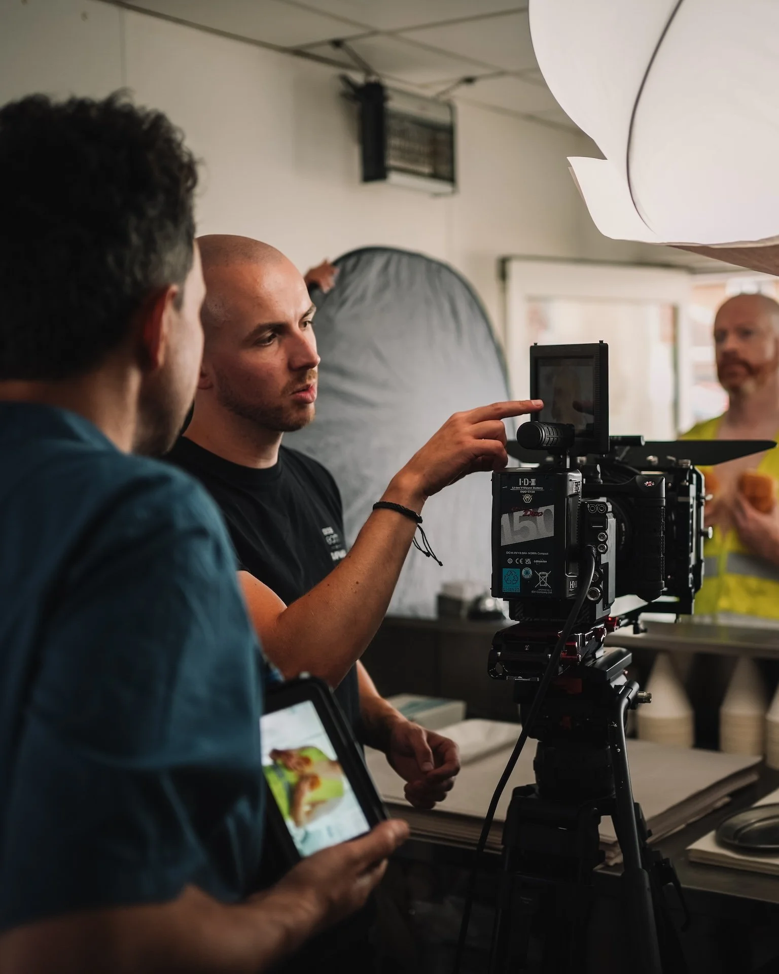 Filmmakers or photographers working on a film or photo shoot, with camera and lighting equipment in an indoor studio.