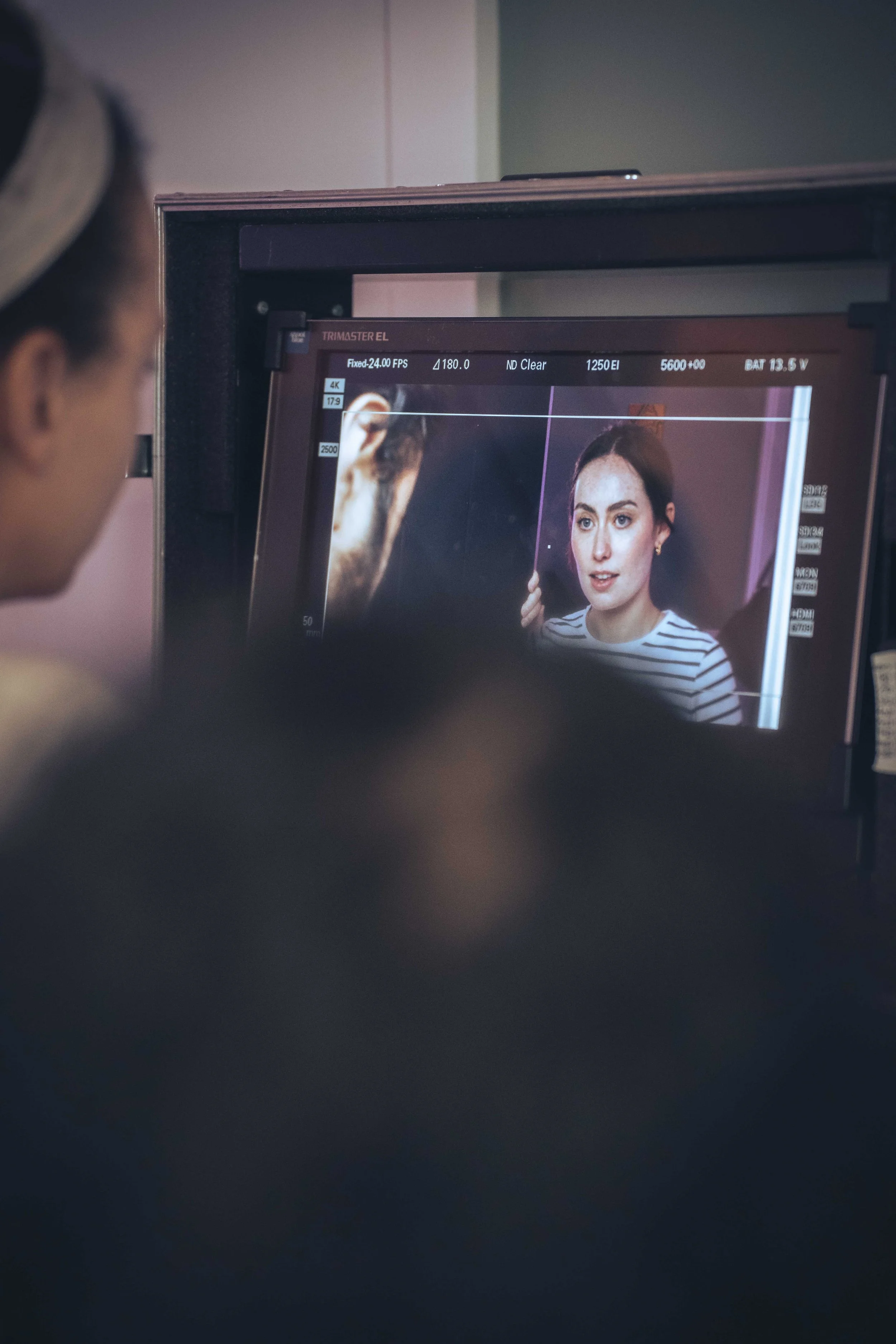 Monitor displaying a photo shoot with a woman in a striped shirt.