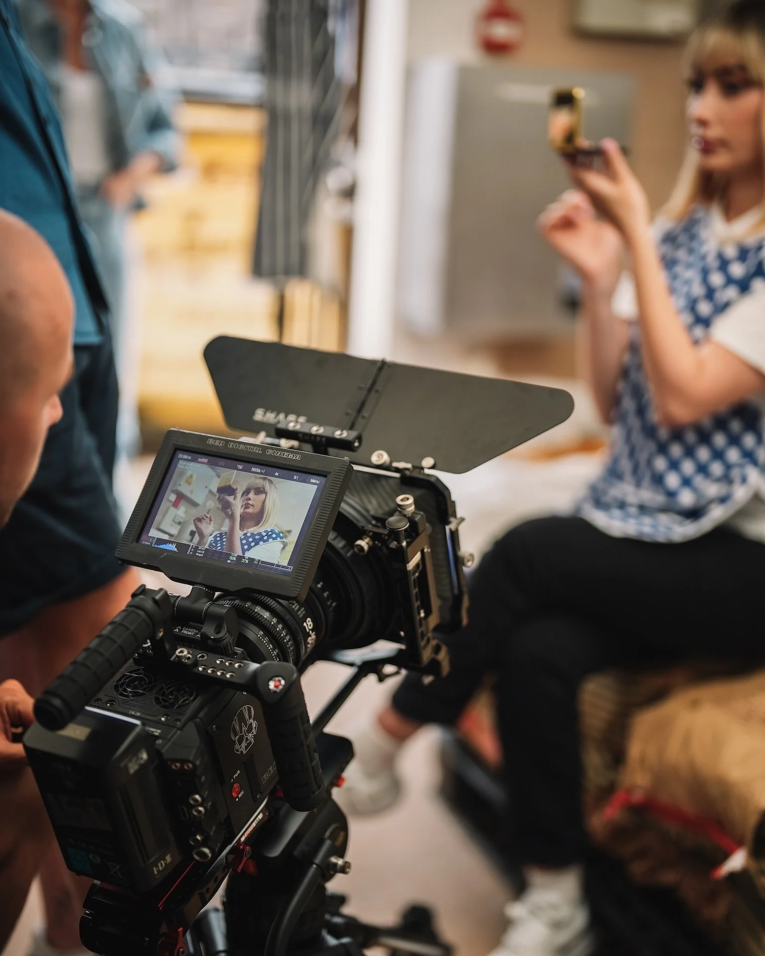 Close-up of a cameraman filming a woman in a polka dot dress holding a fork.