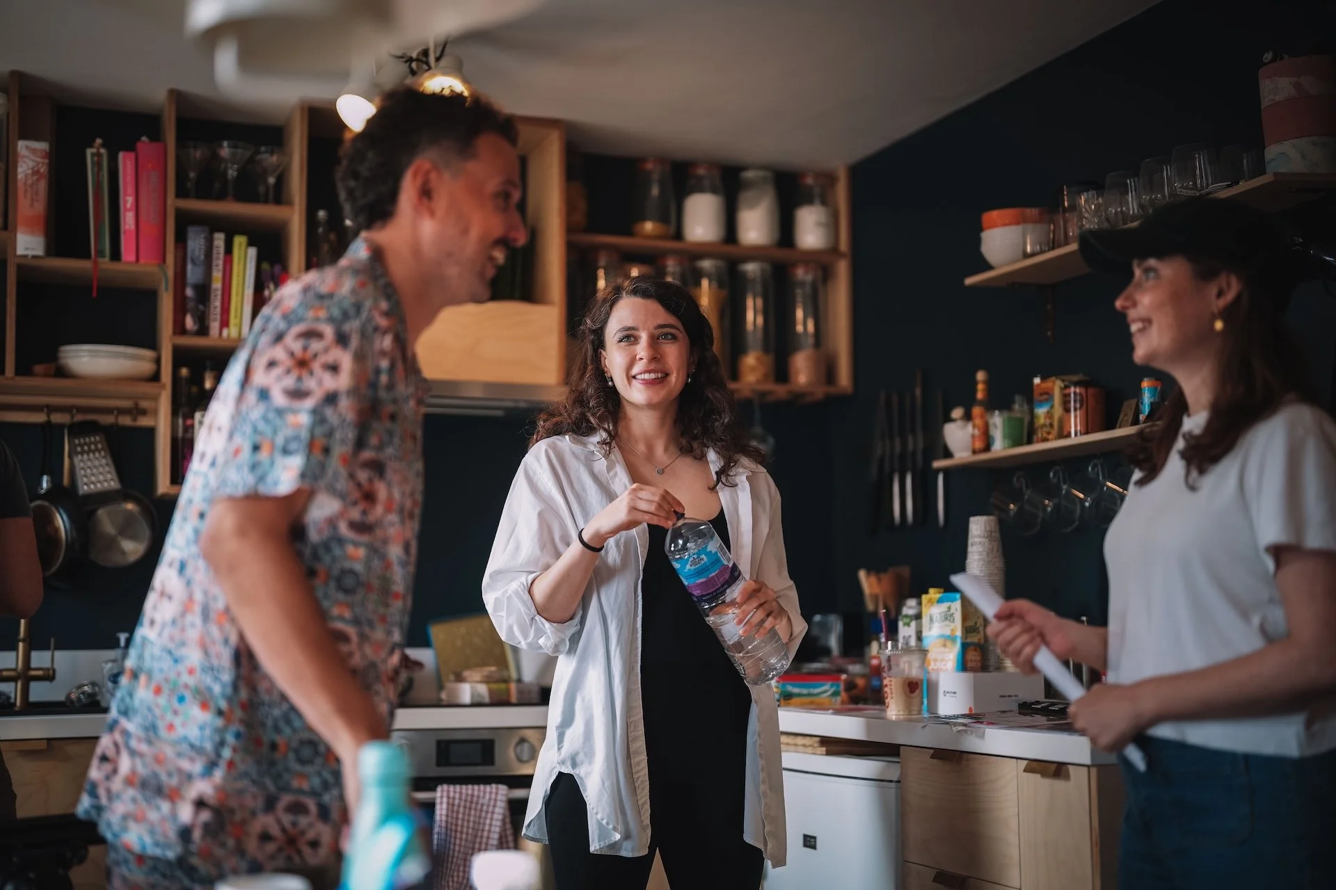 People chatting in a kitchen store, with shelves of kitchenware and food products behind them.