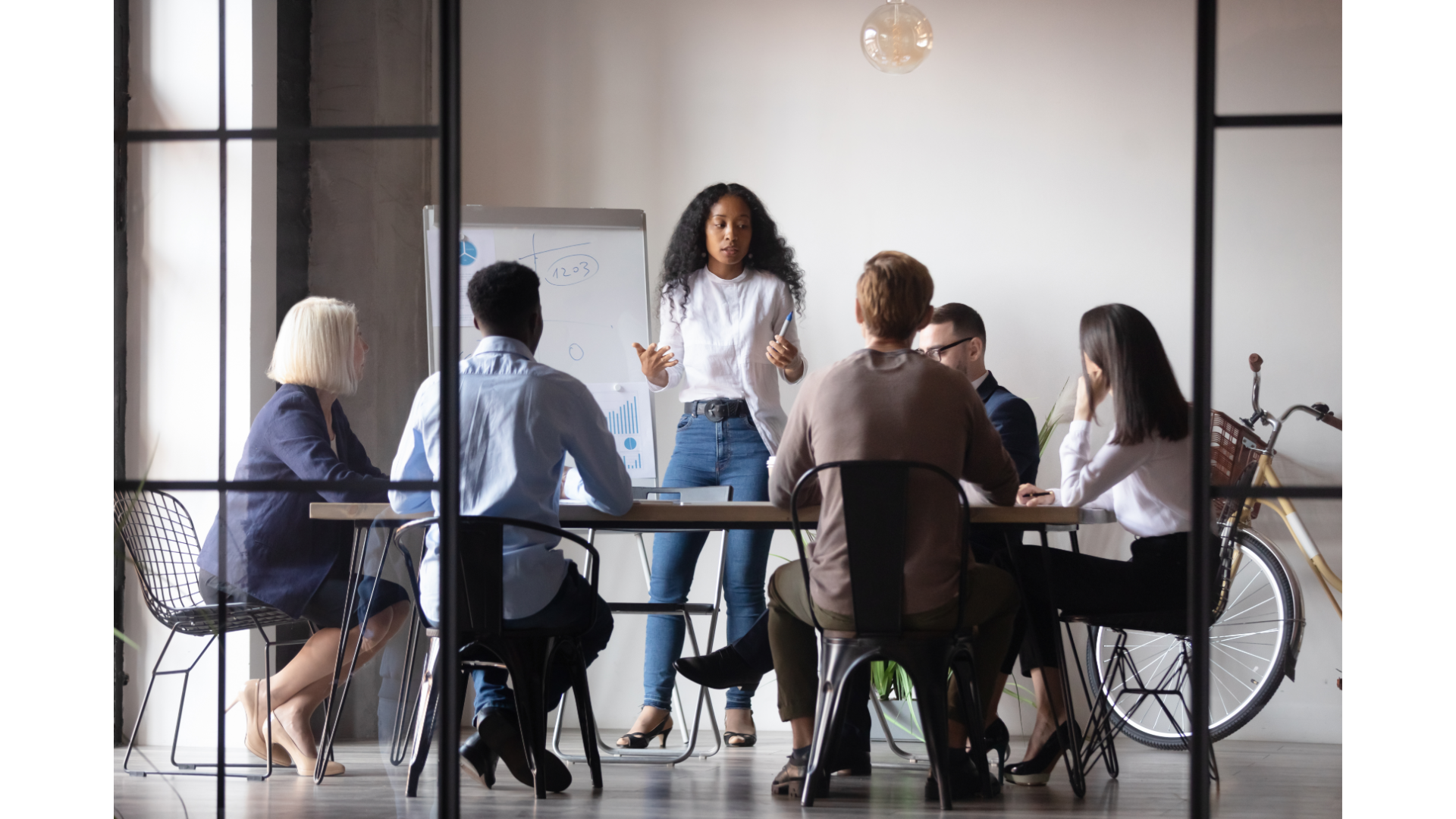 A diverse group of seven people sitting around a table, engaged in a discussion during a community workshop on mental health support.
