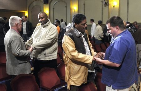 People exchanging handshakes and conversations in a conference room.