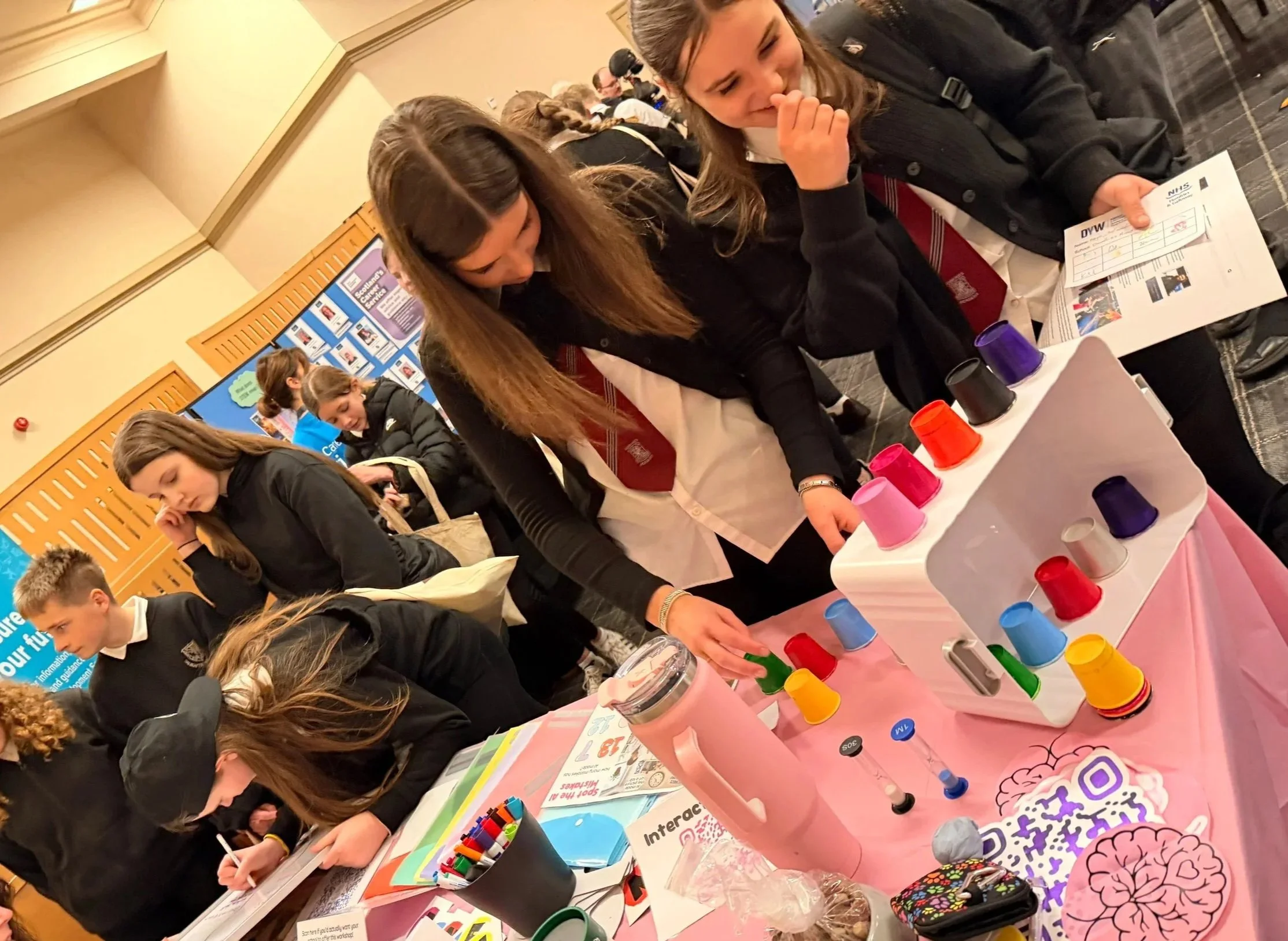Students exploring interactive neurodiversity activities and educational resources at the Kindling Minds exhibition stand during a STEM event.