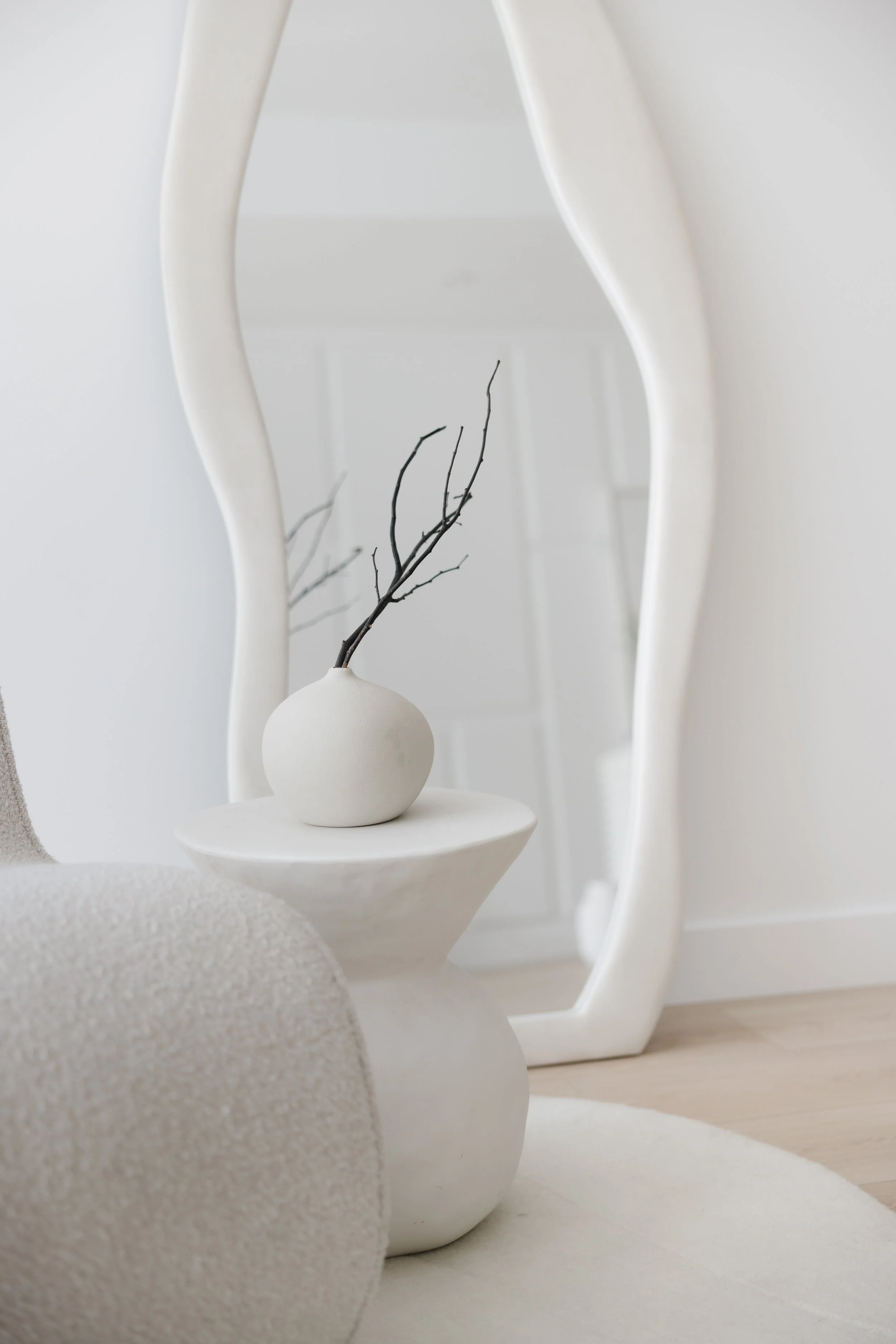 Floor with scattered papers, a smartphone, and sunglasses near a white sofa in a minimalist room.