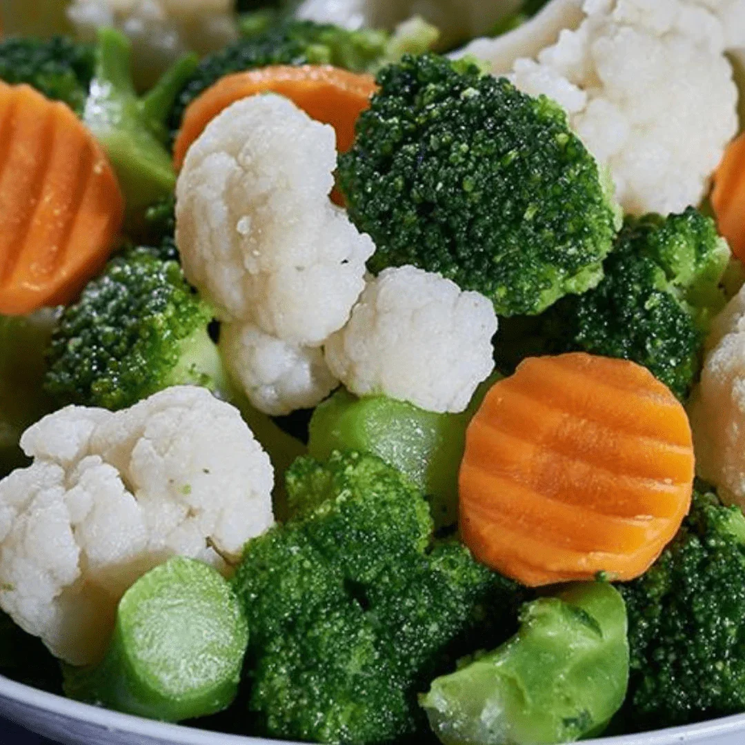 Close-up of steamed broccoli, cauliflower, carrot slices, and green beans.
