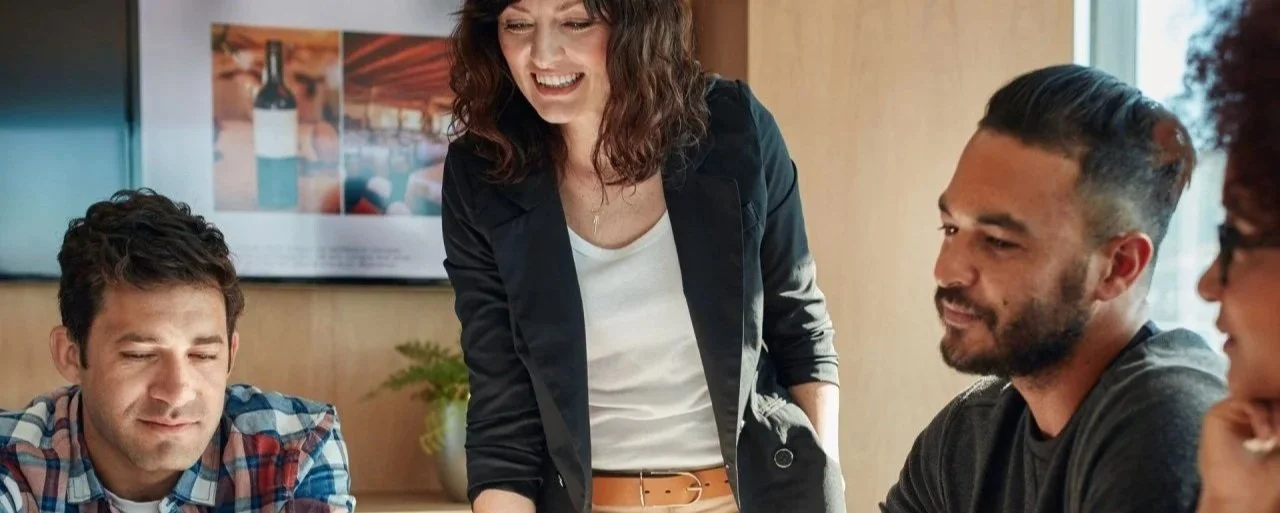 four people sat and stood around smiling and looking at their agency brief