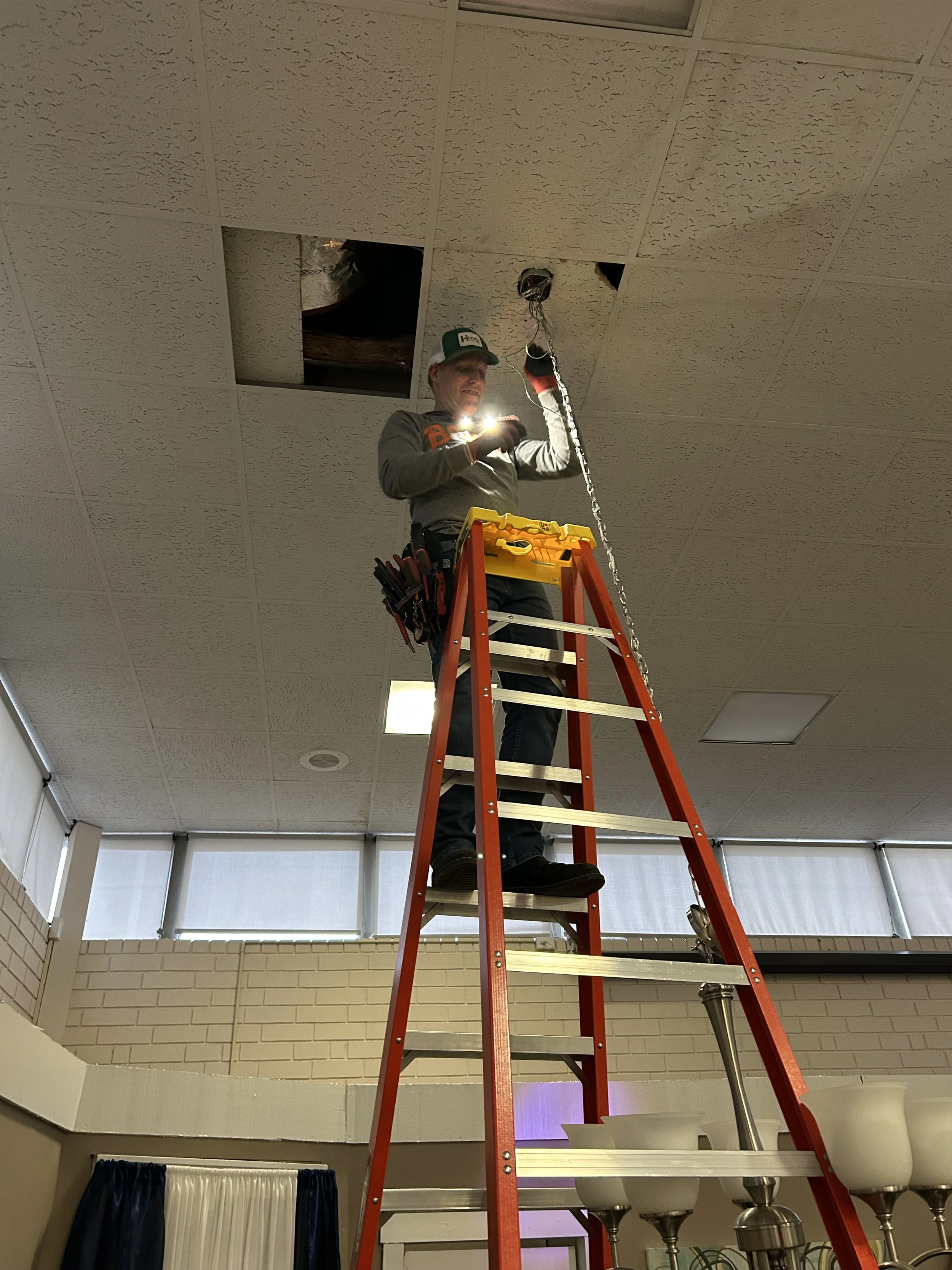 John Flood installing chandelier at Big Charms Players theater space