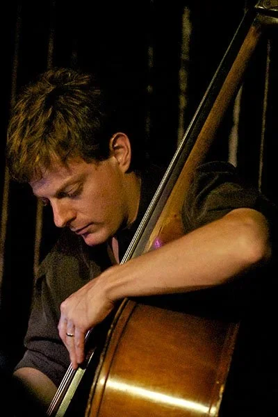Dan Feiszli. A young man playing a double bass on stage, concentrating on his performance.