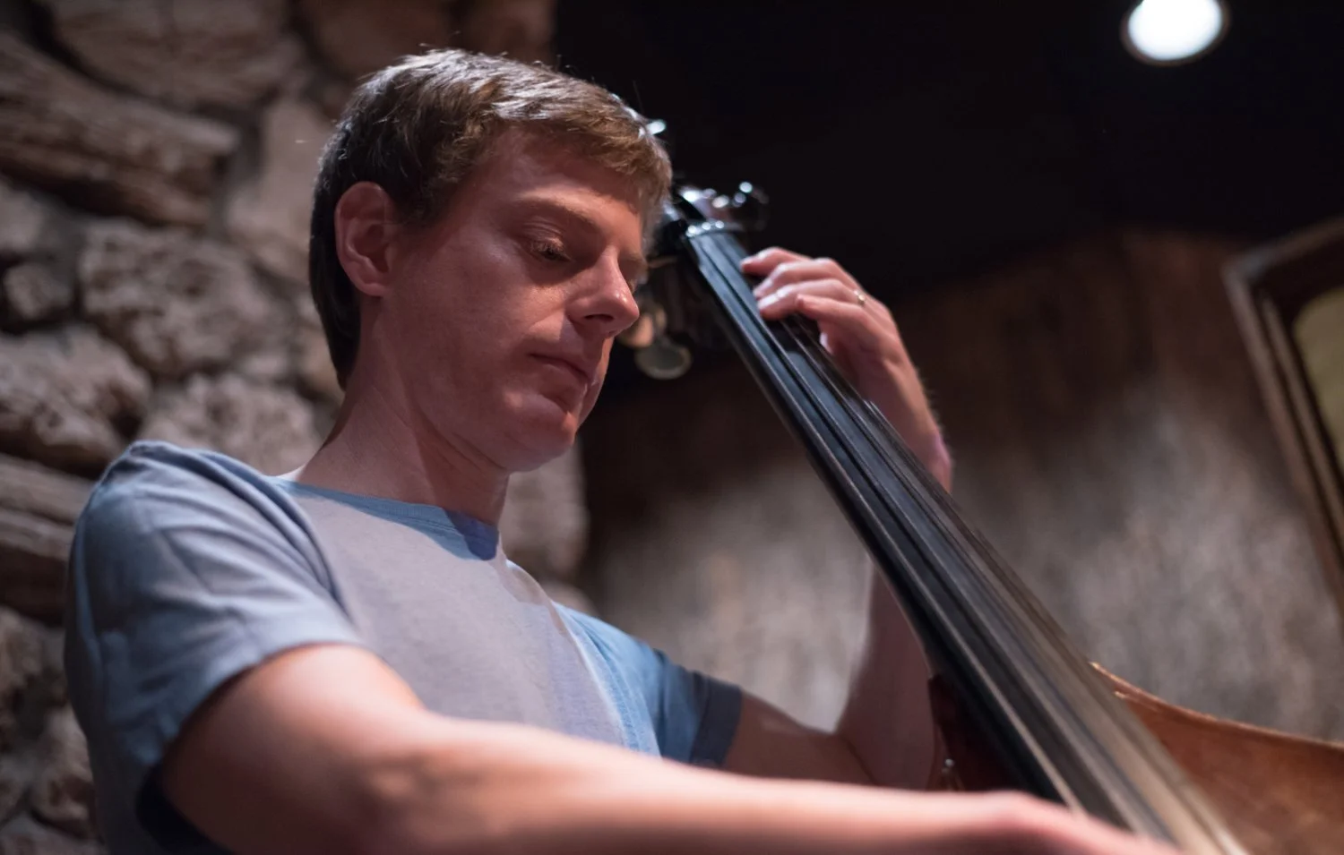 Dan Feiszli. A young man playing a double bass on stage, concentrating on his performance.