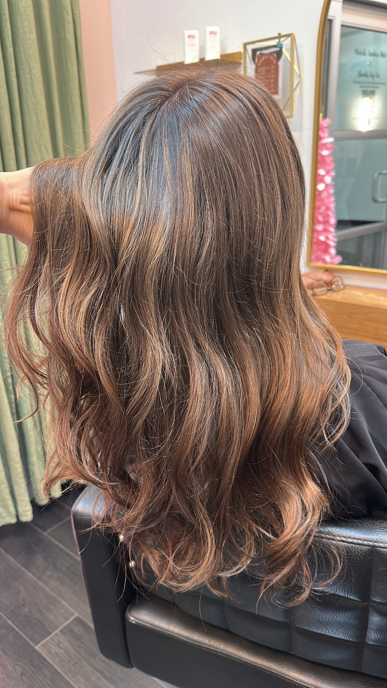 Back view of a client with shoulder-length wavy brown hair.