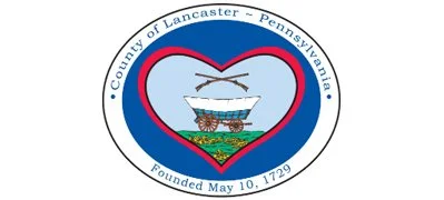 The seal of Lancaster County, Pennsylvania, featuring a heart shape, a white boat, and a green landscape.