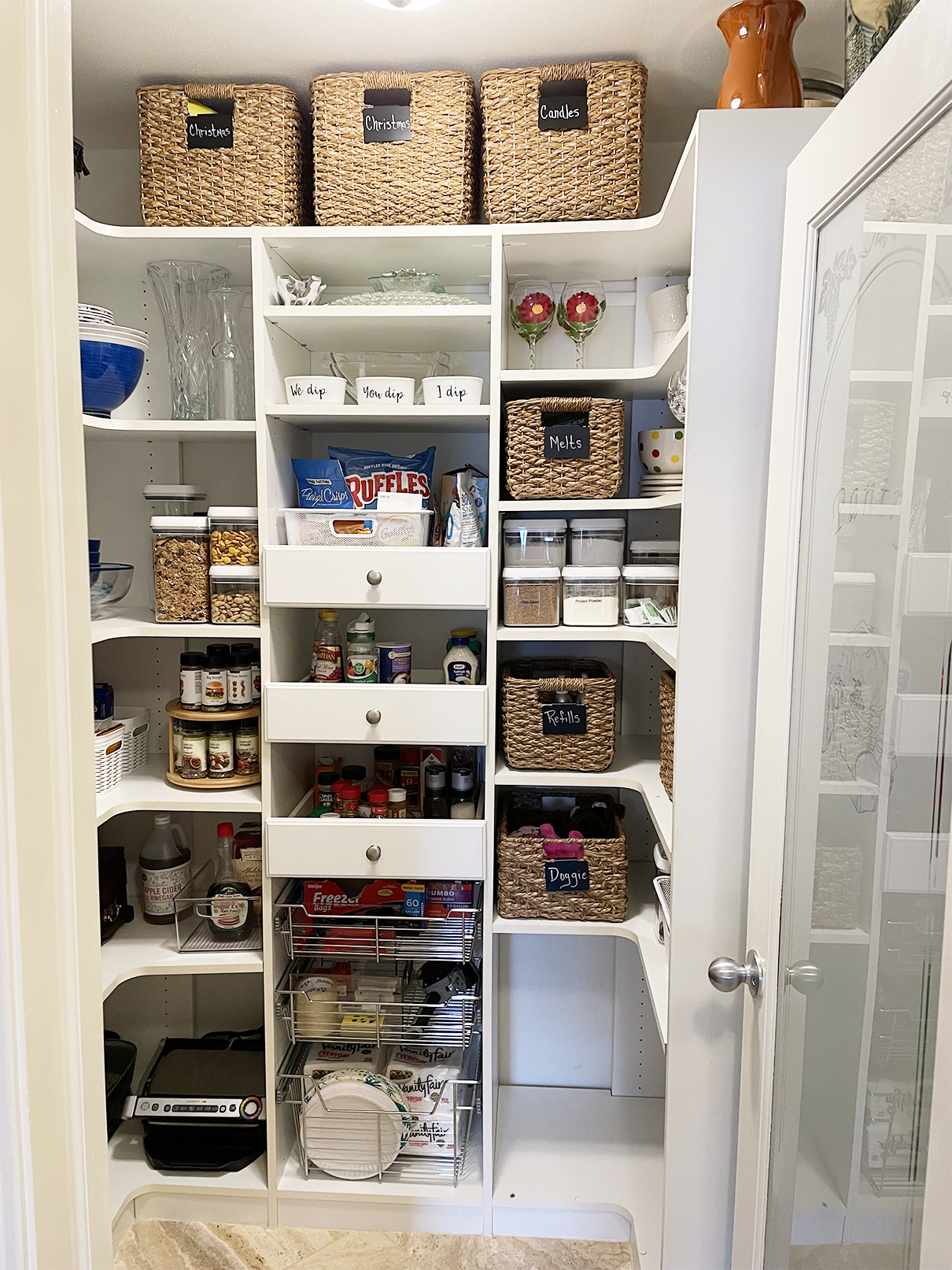 A kitchen pantry utilizing labeled bins and a visual sorting system.