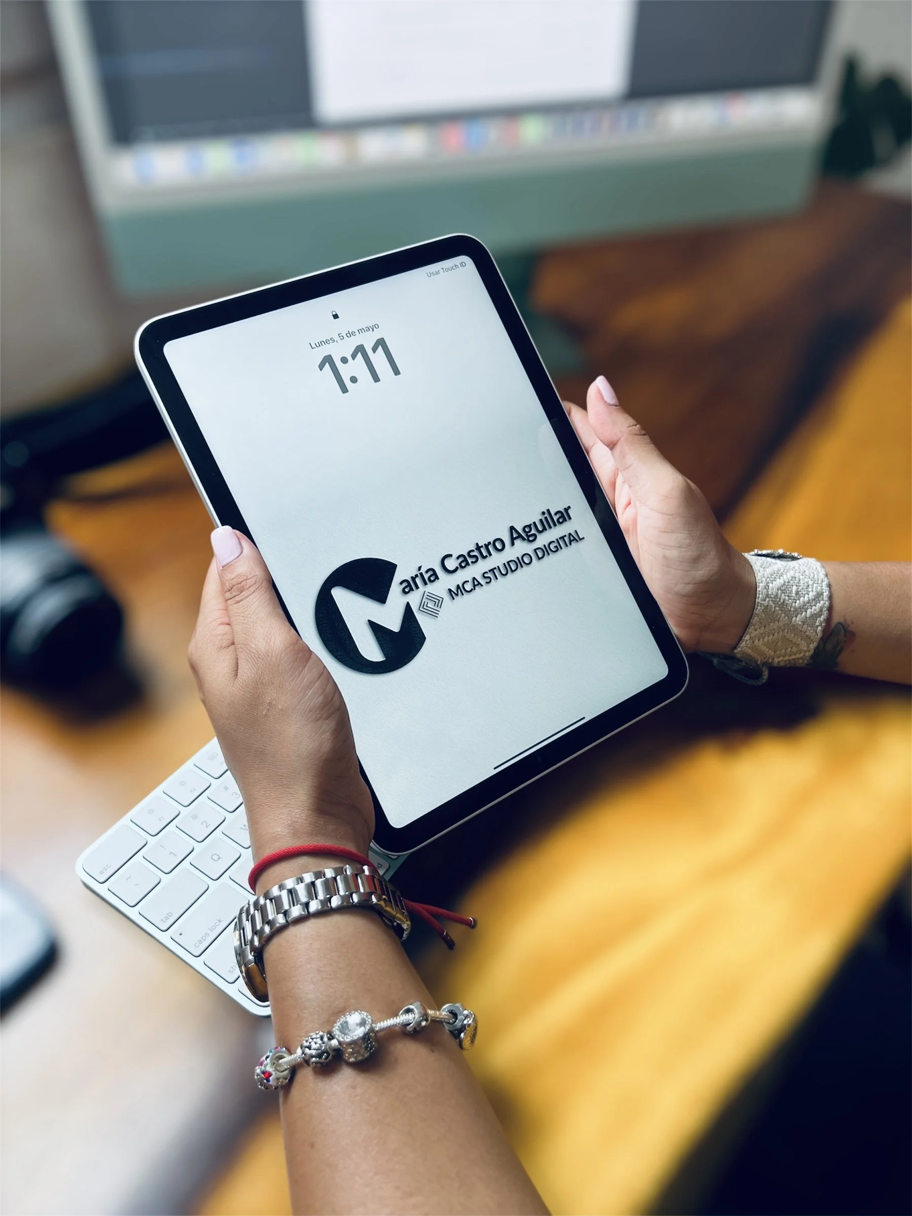 Persona sosteniendo una tableta digital que muestra un logotipo y la firma 'María Castro Aguilar MCA STUDIO DIGITAL', en un entorno de oficina.