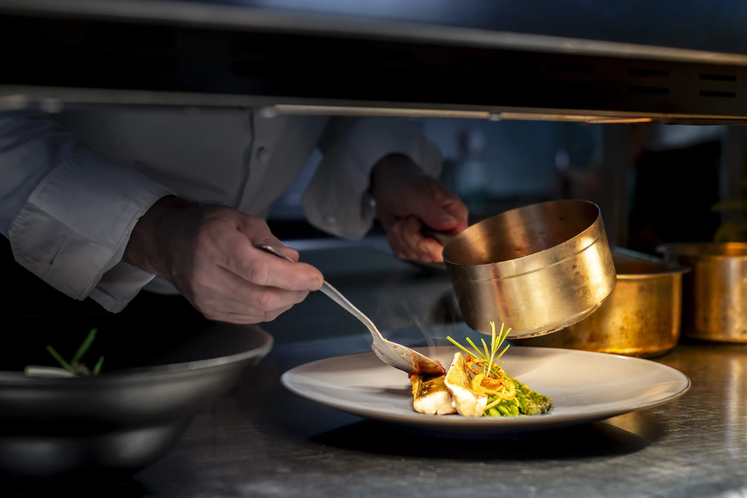 Chef plaçant des éléments de décoration sur un plat gastronomique dans une cuisine professionnelle.