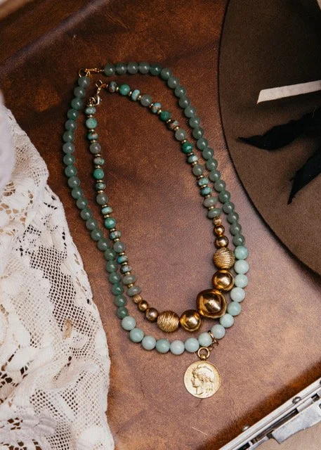 A necklace with aqua green and gold beads, featuring a gold medallion pendant