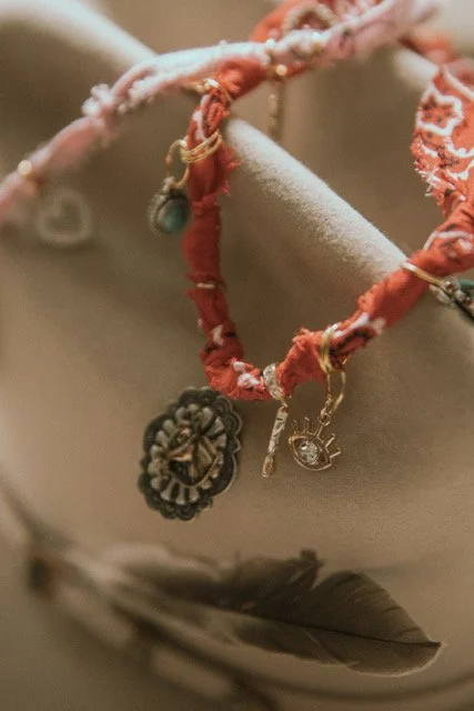 Close-up of a fabric jewelry holder with layered necklaces, including one with a floral pendant, a small key, and a tiny eye charm, along with various other jewelry pieces.