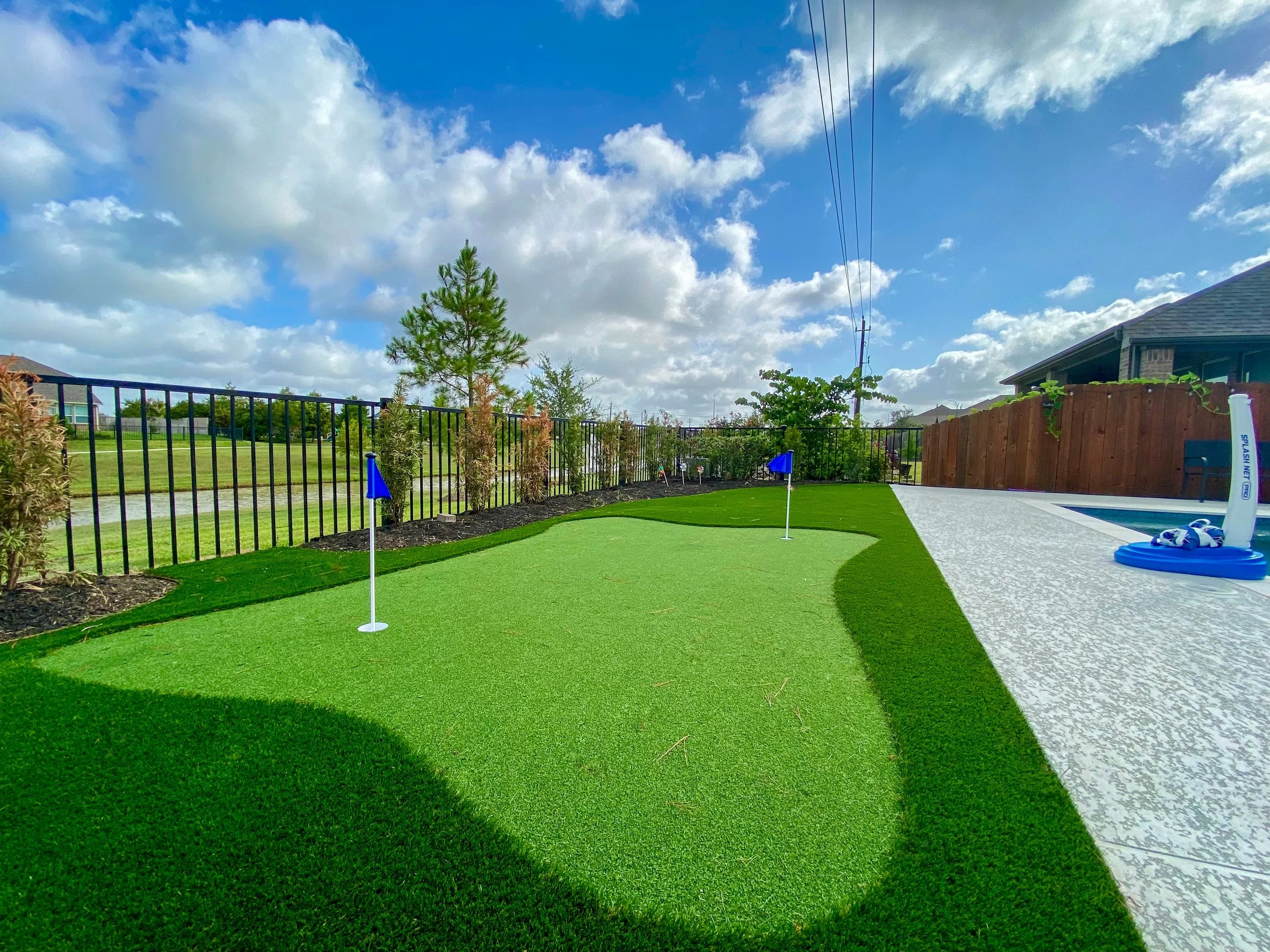 Artificial turf golf hole next to a pool.