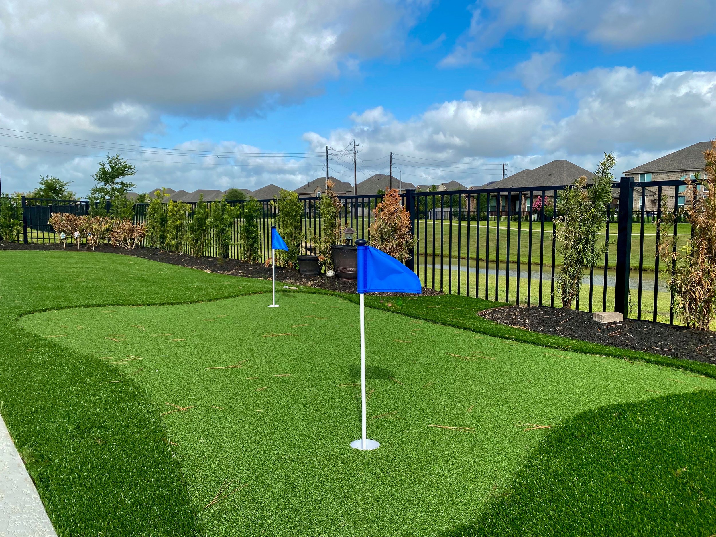 Artificial turf mini golf next to a fence.