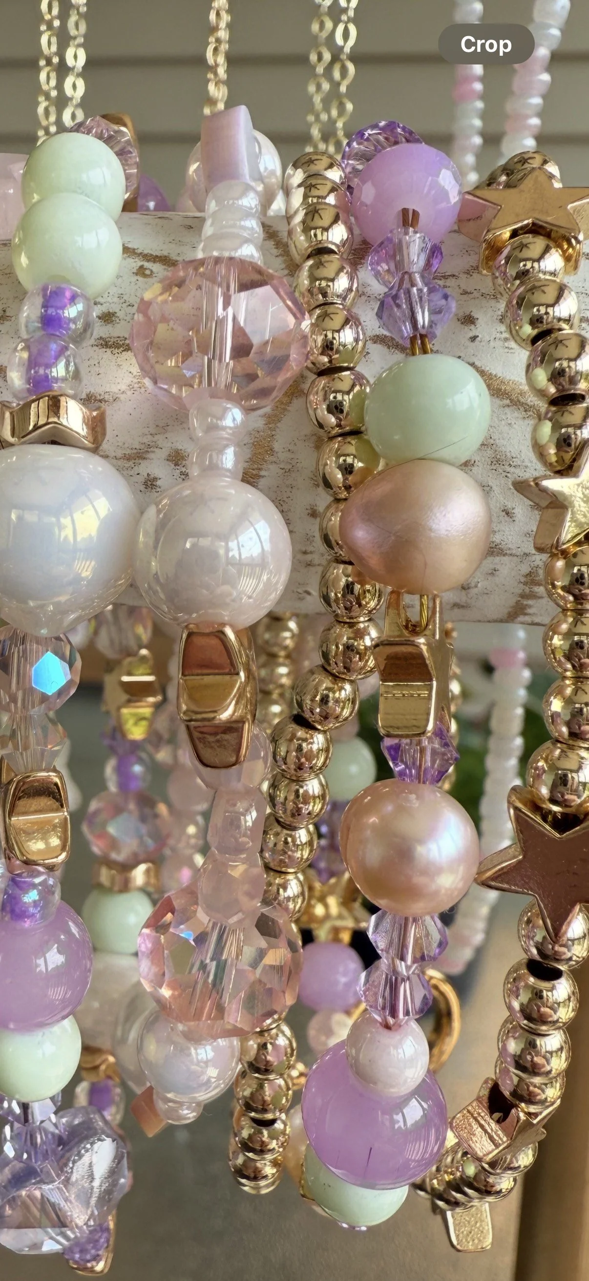 Close-up of beaded jewelry with pastel-colored beads, including pink, purple, green, and peach, hanging on display.