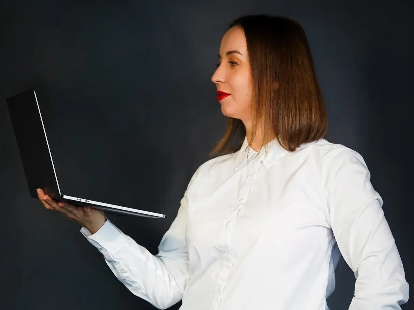 Woman in white shirt holding a laptop