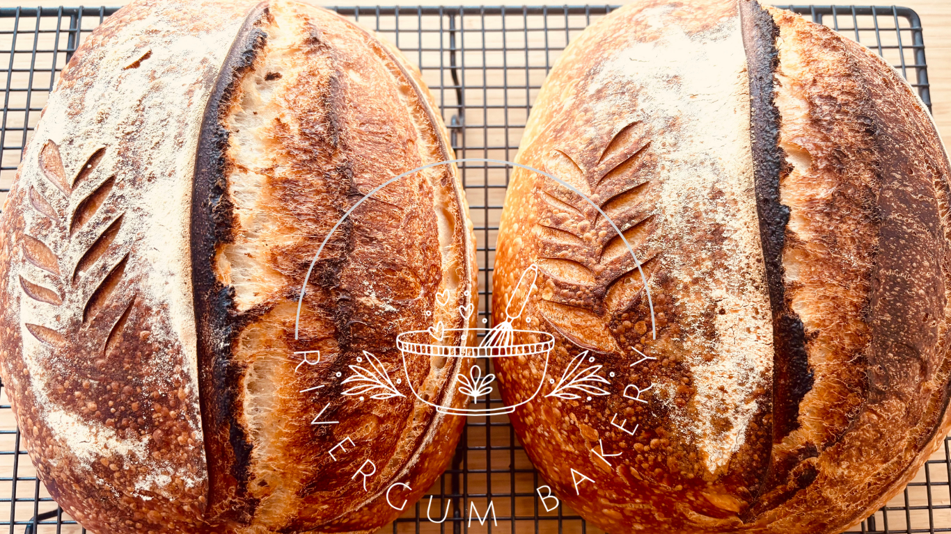 Two loaves of bread cooling on a wire rack, featuring a decorative leaf pattern on the crust.