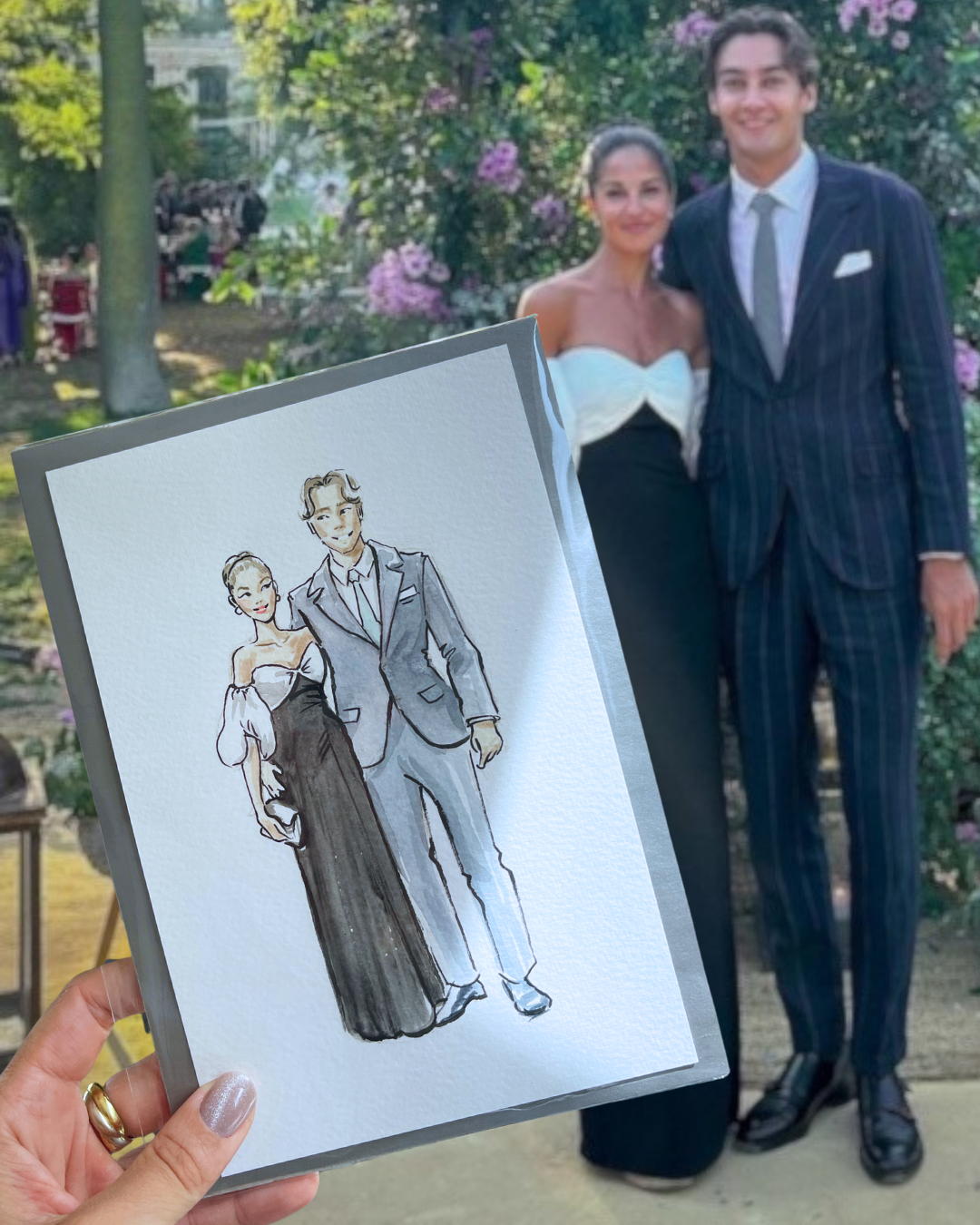 Portfolio: live wedding painting — couple holding bespoke watercolour illustration outdoors, live event portrait art by Kimberly Djehanian London