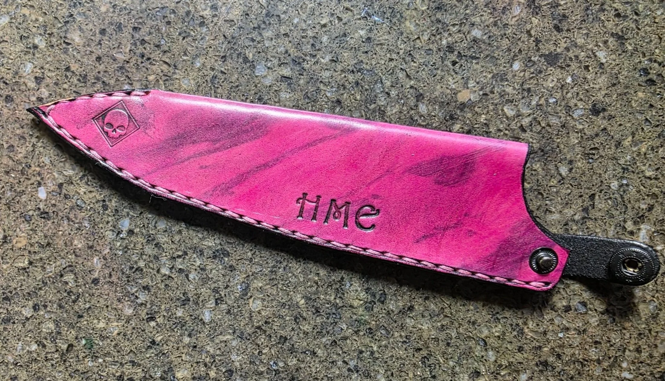 A standard sheath, with Pink base, and black Marbling, and initials and little square skull stamp, and a button Add-on.