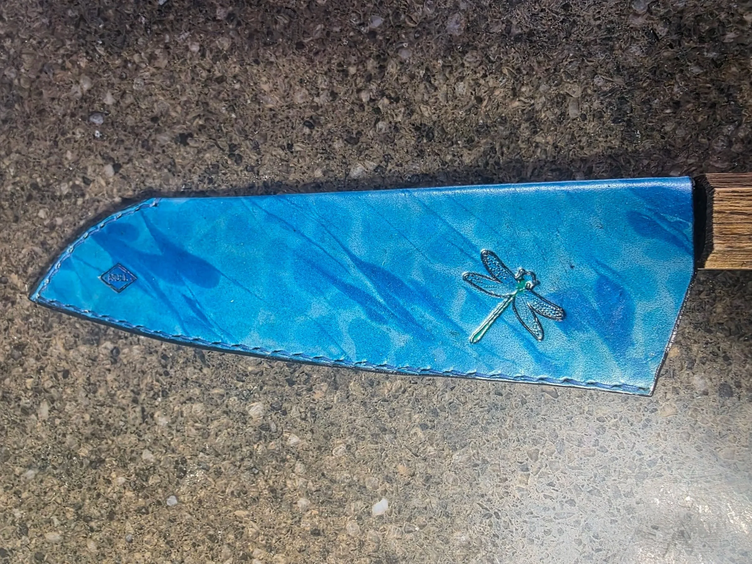 A full size sheath for a Santoku, made with a water theme, it has a Turquoise base with Blue airbrush and Blue marbling, with large dragonflies, painted green.