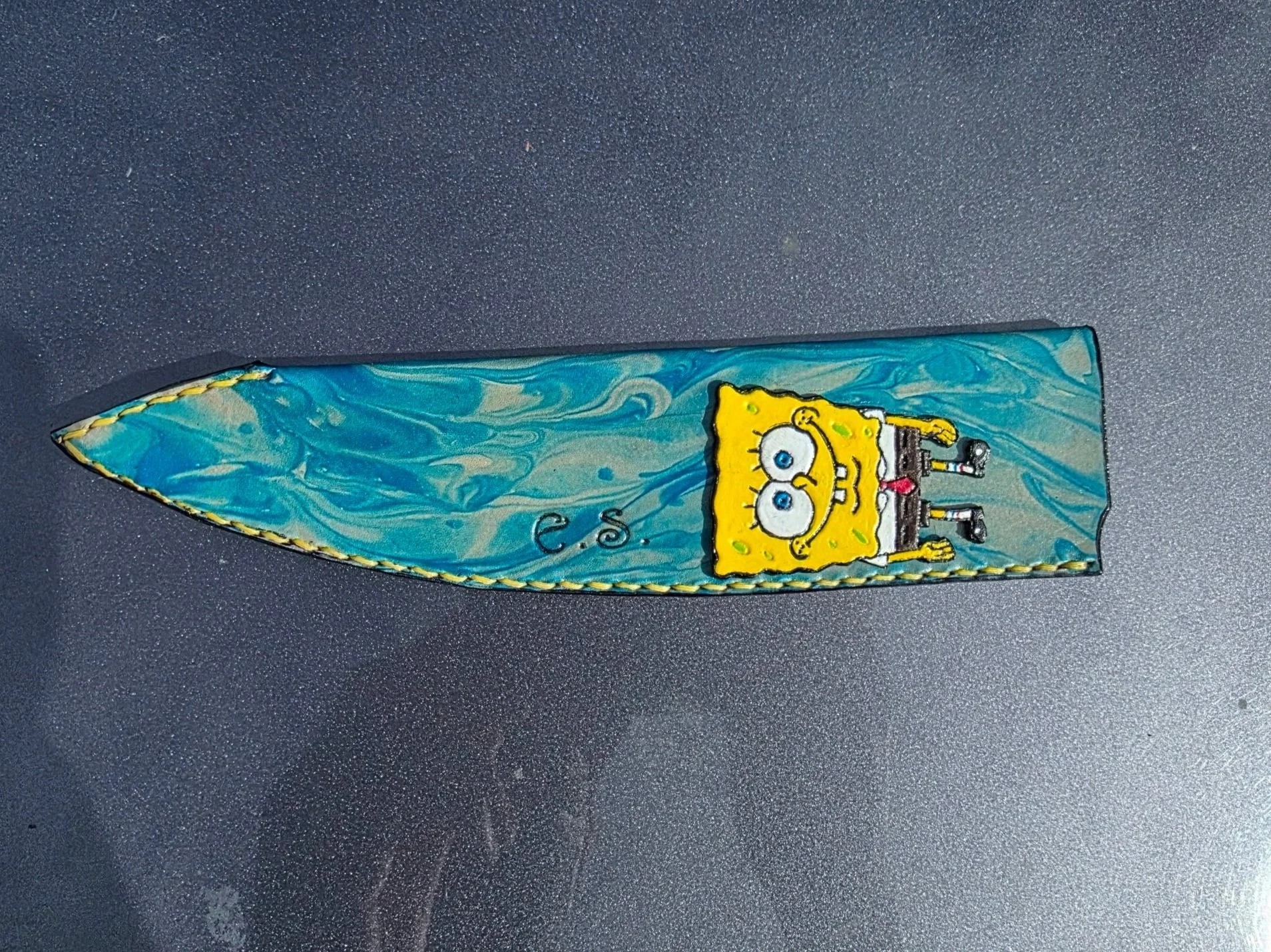 A custom full-size sheath, with a turquoise, and blue marble base, with a custom painted Spongebob patch, and flower engraving.
