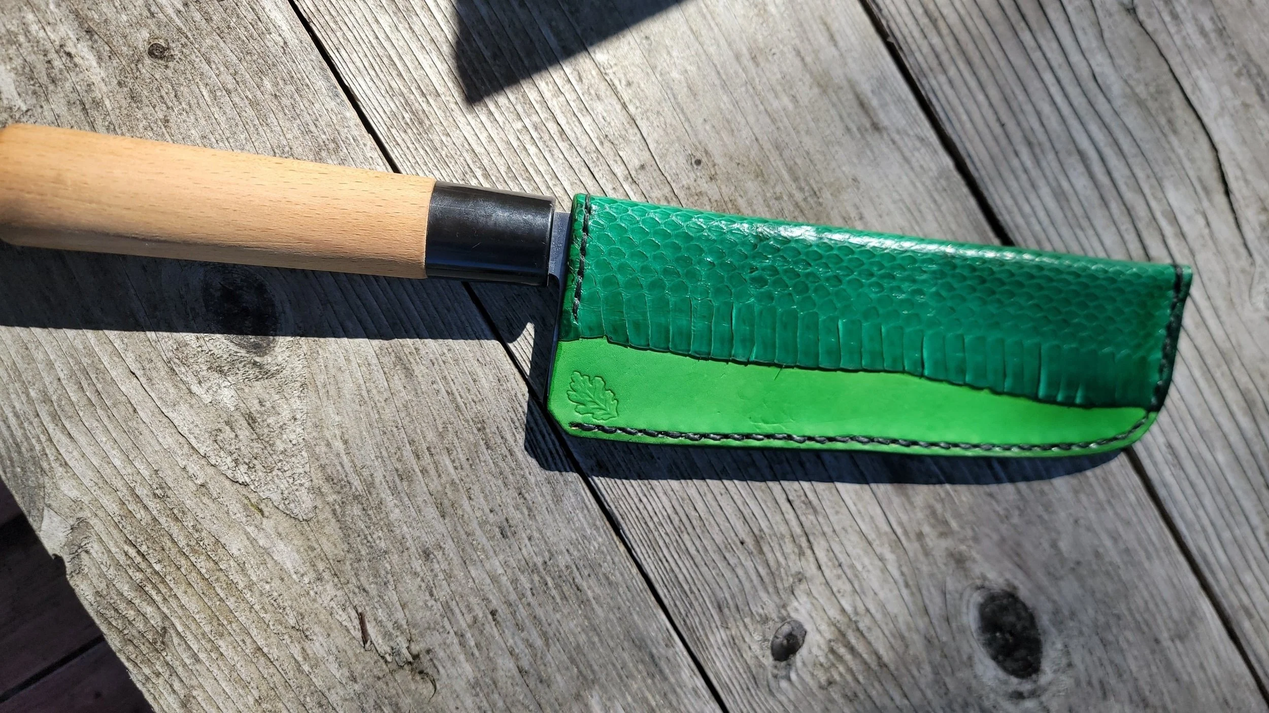 A personal single beveled nakiri with kelly green, and added snake leather panel, along with oak leaf stamp.