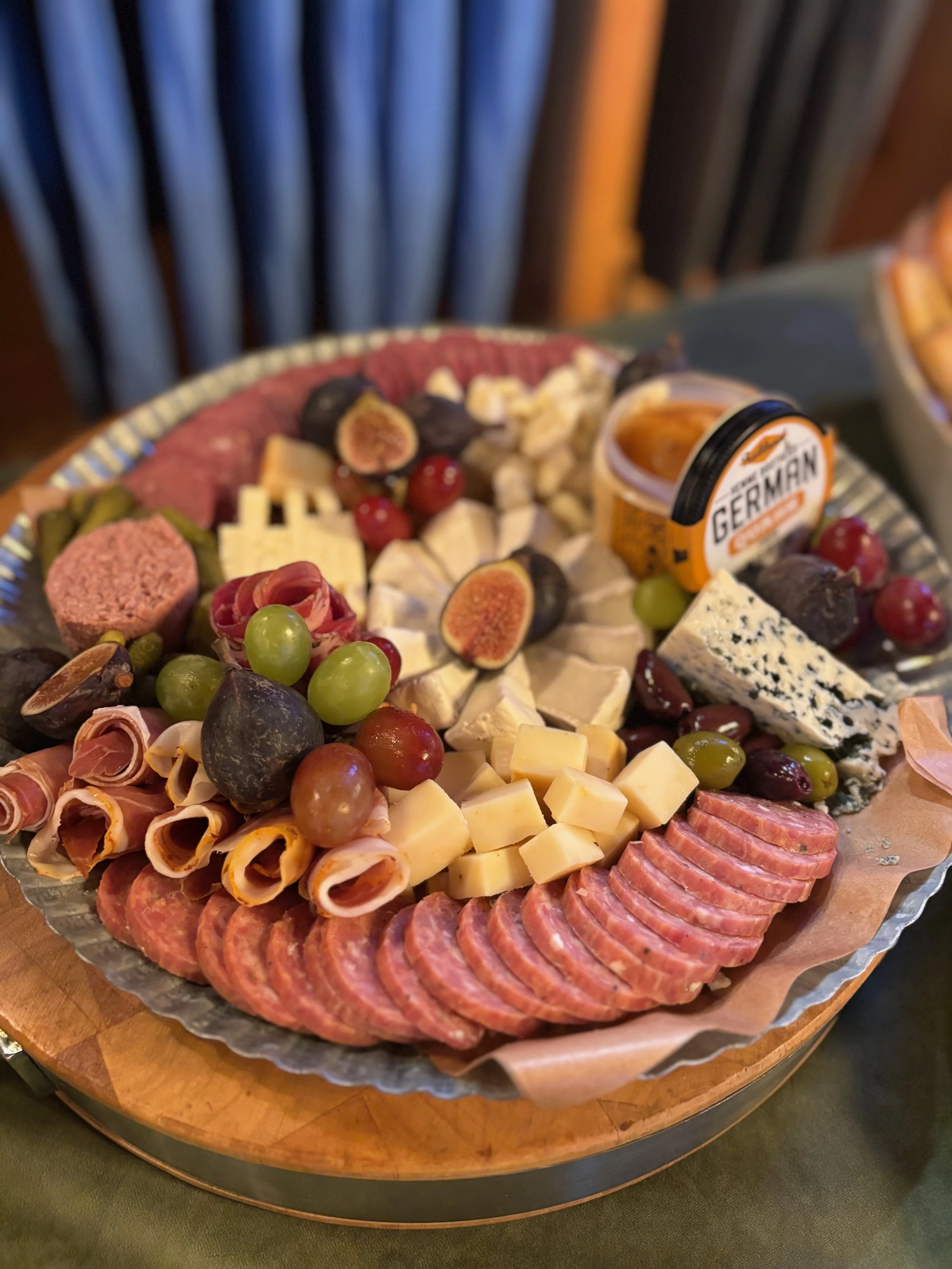 A cheese and charcuterie platter with grapes, figs, olives, meats, and local cheeses.