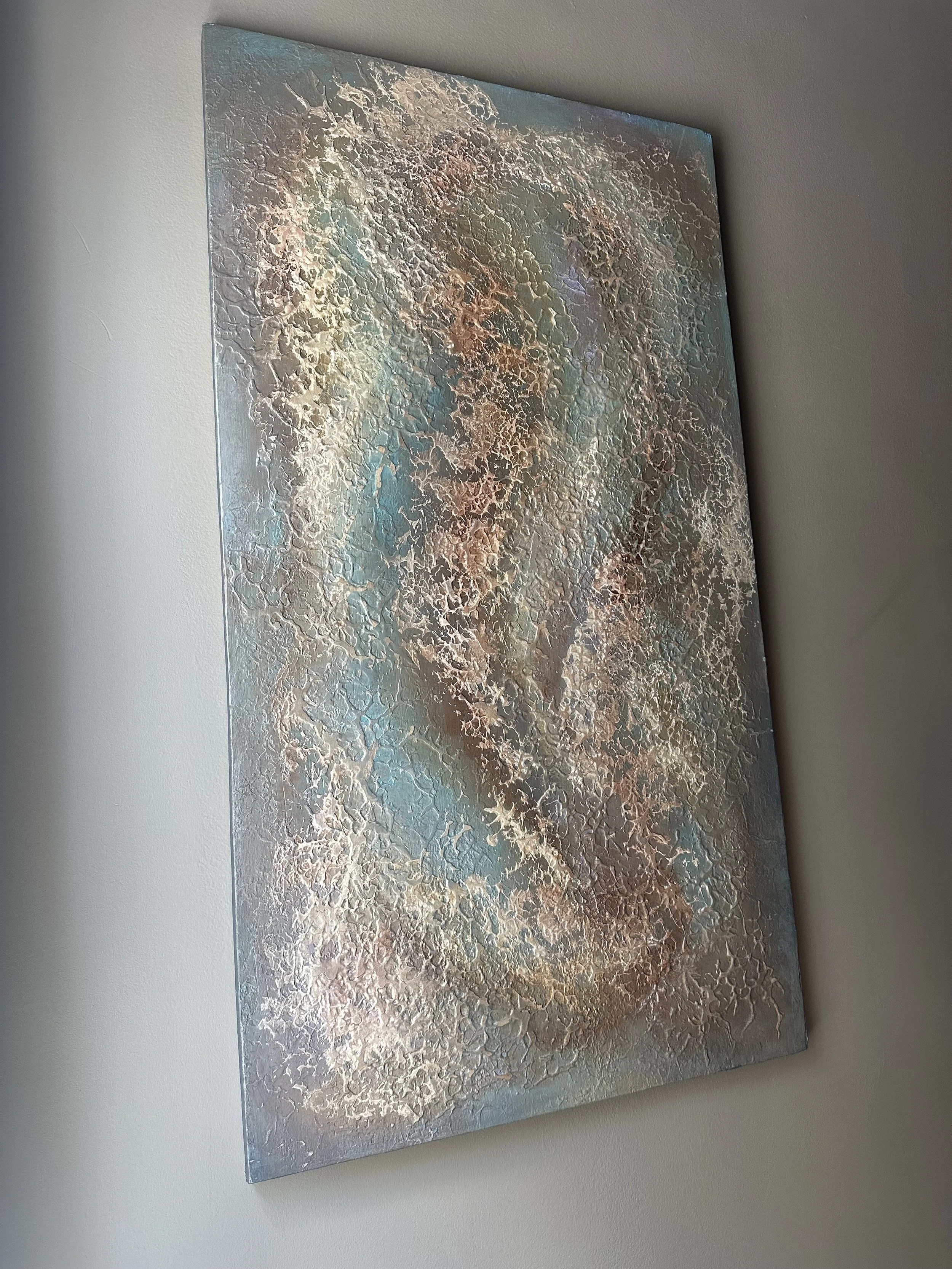 Abstract textured painting with swirls of blue, white, beige, and copper colors hanging on a white wall.