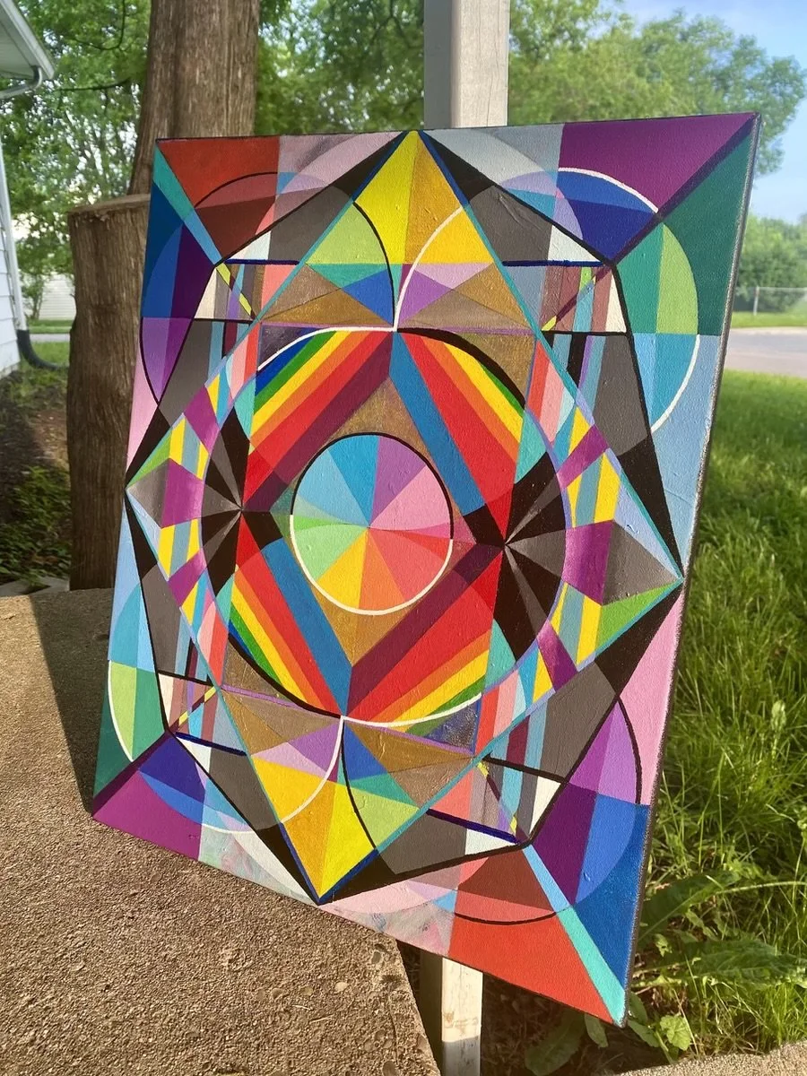 Colorful geometric abstract painting featuring circles, triangles, and squares with rainbow colors and bold black outlines, displayed outdoors.