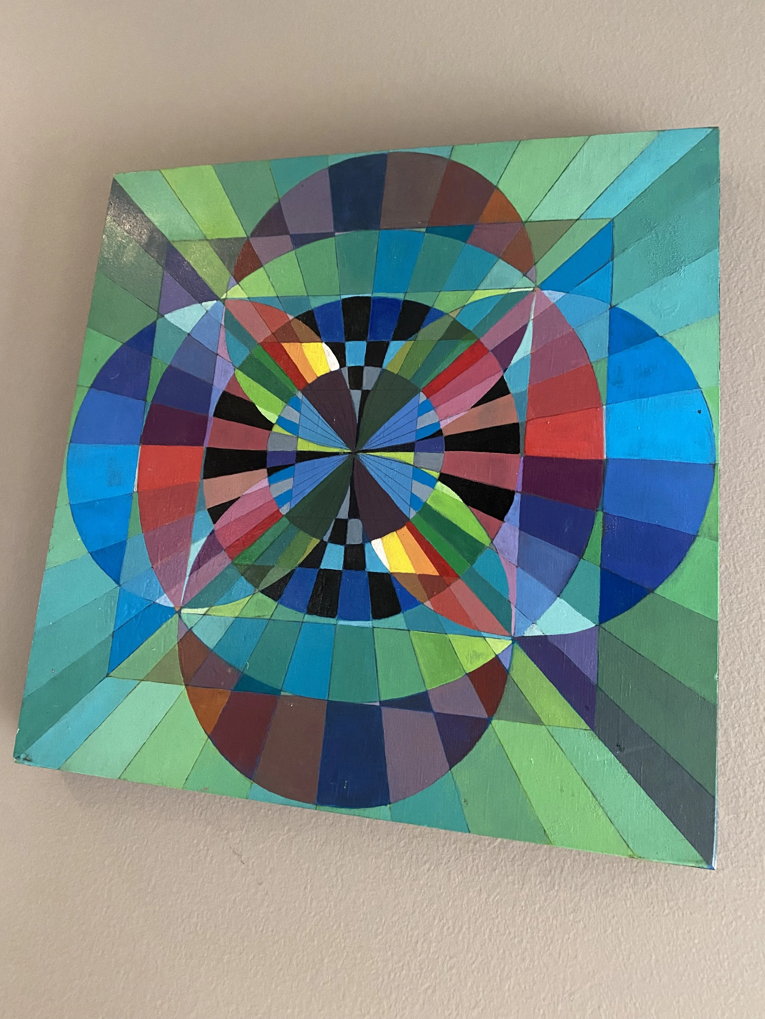 Colorful geometric abstract painting with concentric circles, triangles, and diamonds in shades of blue, green, red, yellow, and black.