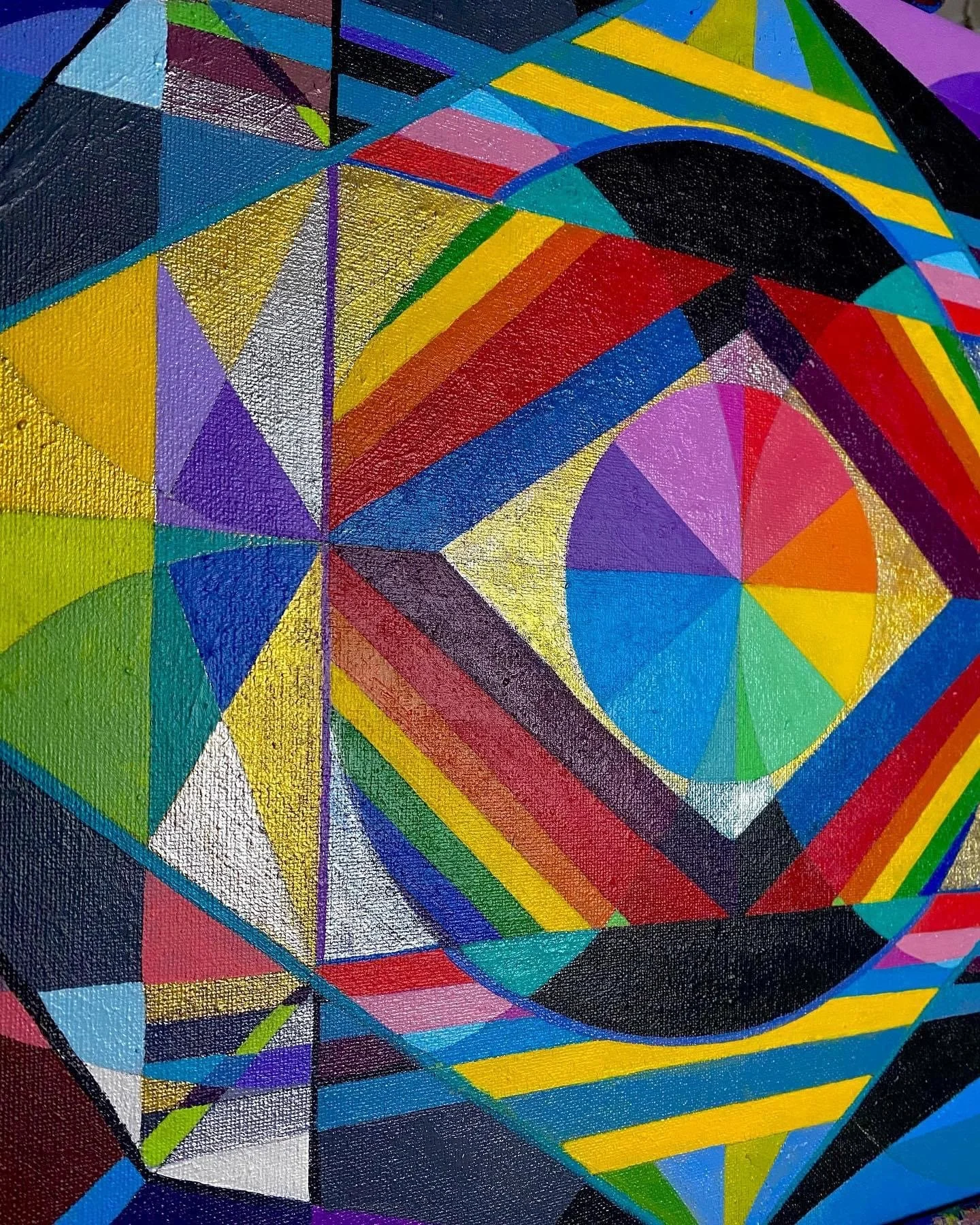Close-up of a colorful geometric abstract painting with various triangles, circles, and lines in bright colors like yellow, red, blue, green, purple, and black.
