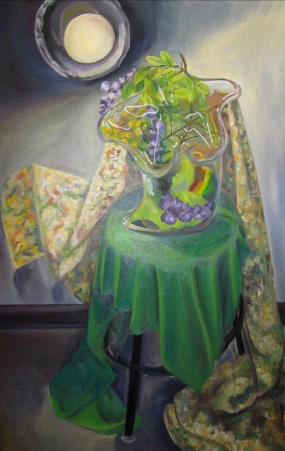 A painting of a still life scene featuring a glass pitcher with green leaves and purple grapes, placed on a small green table covered with a green cloth. There are two floral-patterned napkins, one fold over the other, on either side of the pitcher.