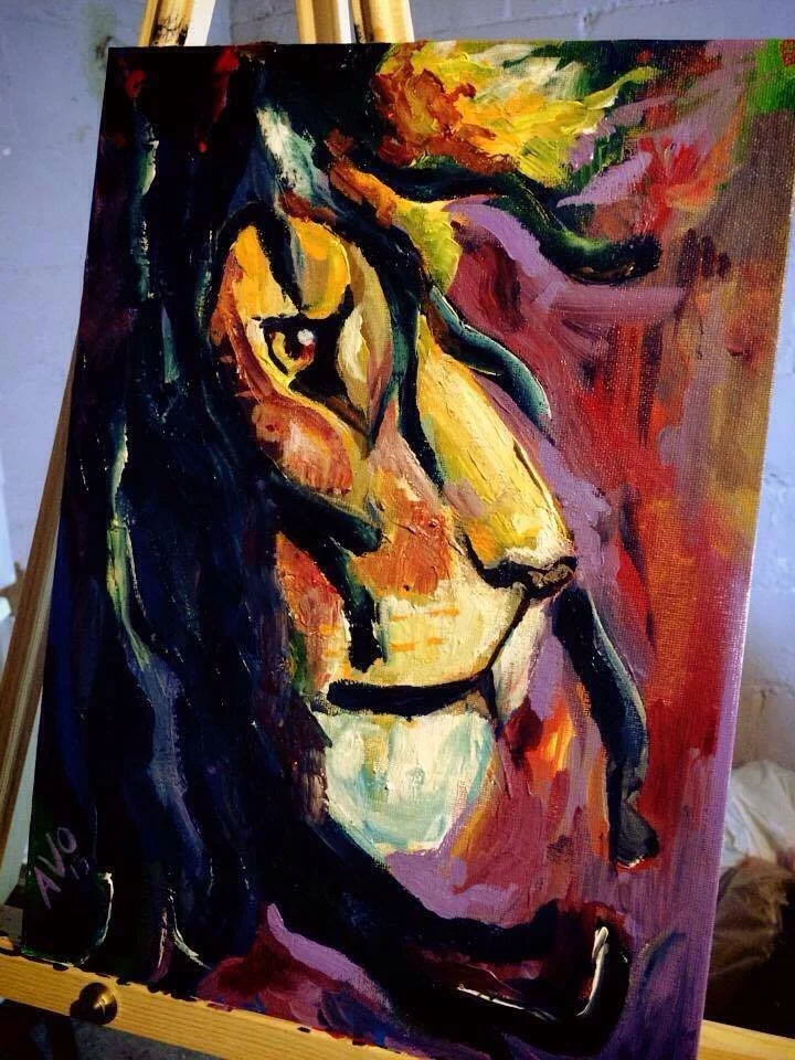 A colorful abstract painting of a lion's head on a canvas, placed on an easel.