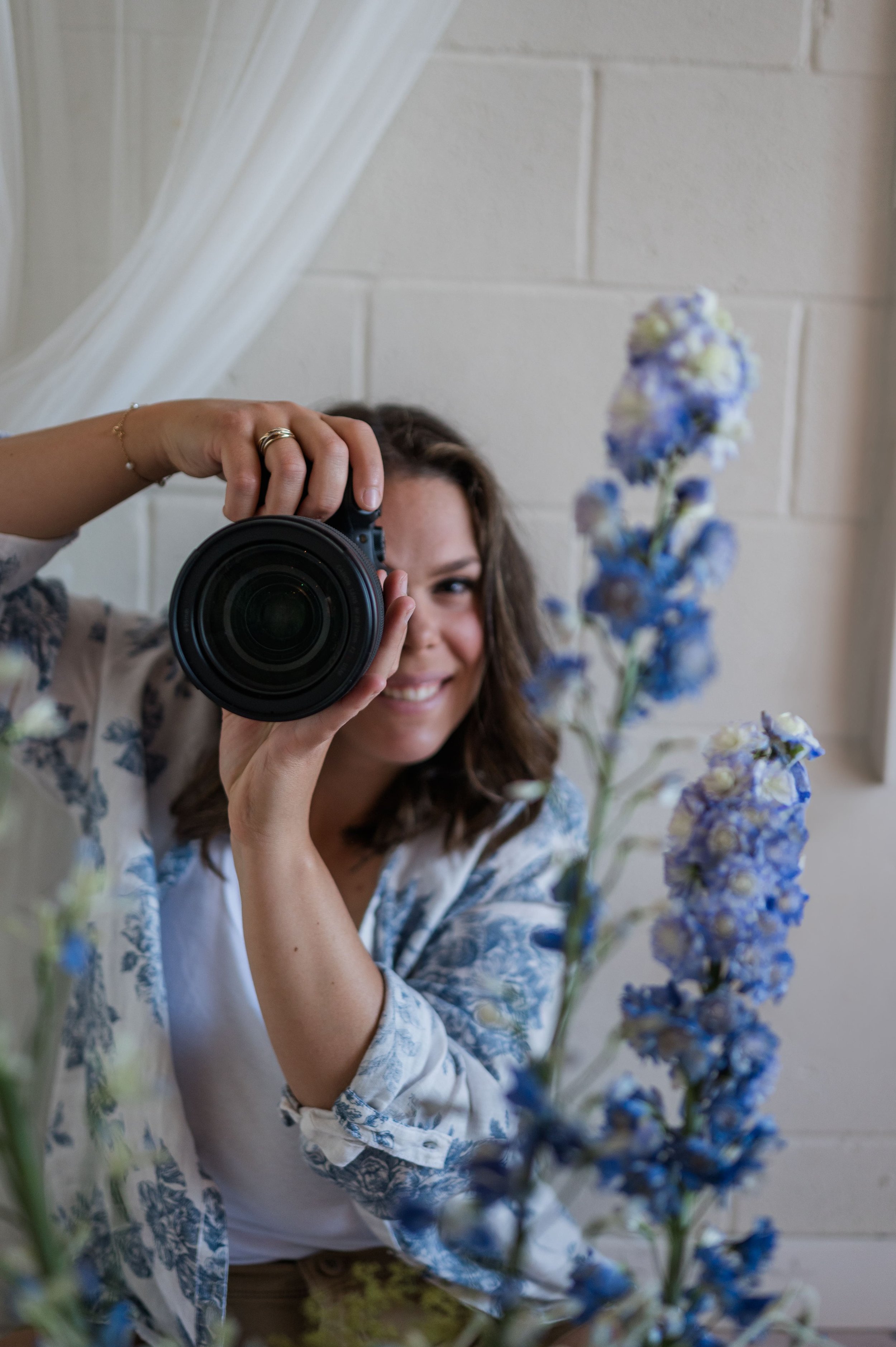 branding session for a french photographer holding her camera behind flowers
