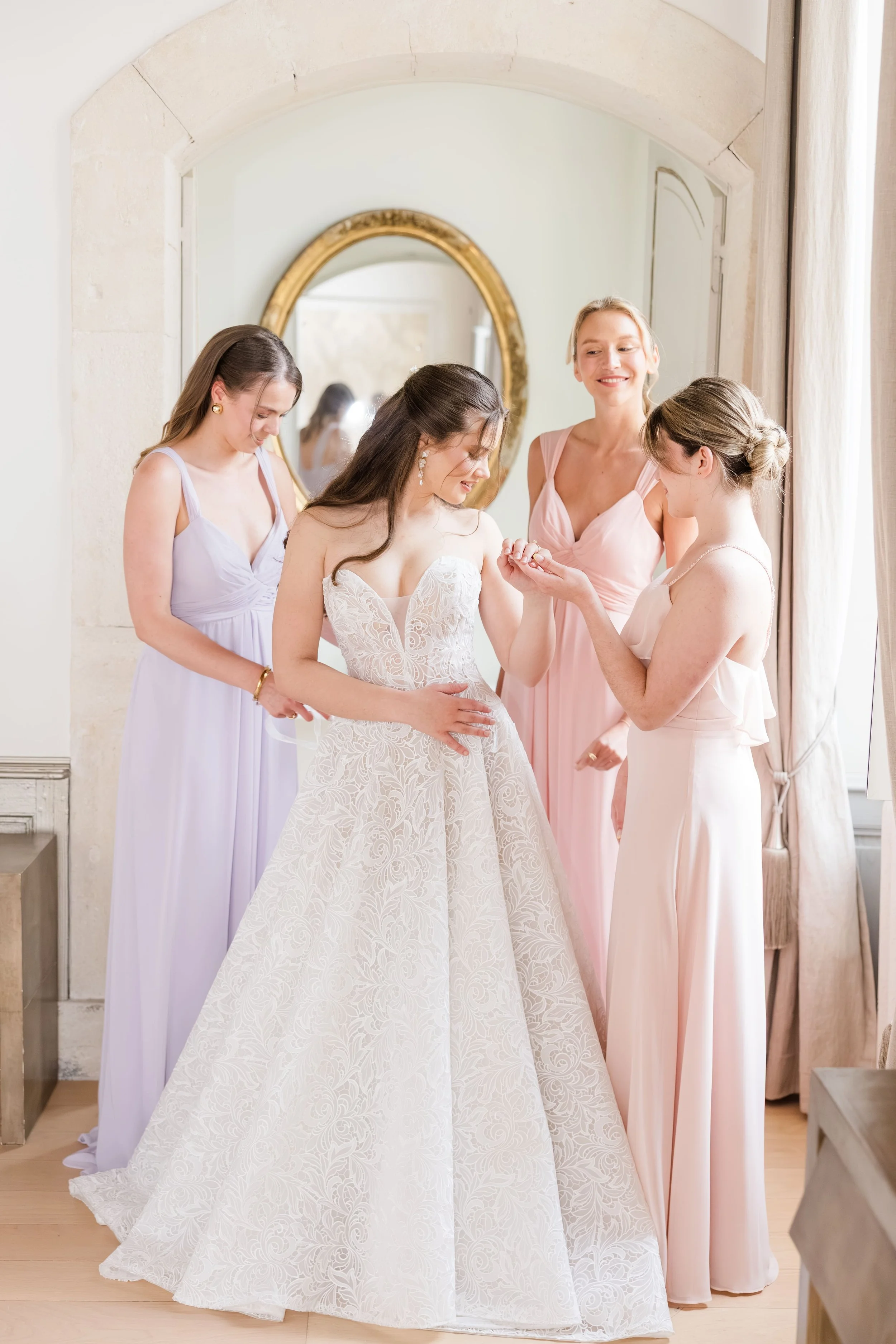 Bridal party moment with bridesmaids adjusting the bride’s dress, styled in soft blush and natural tones.