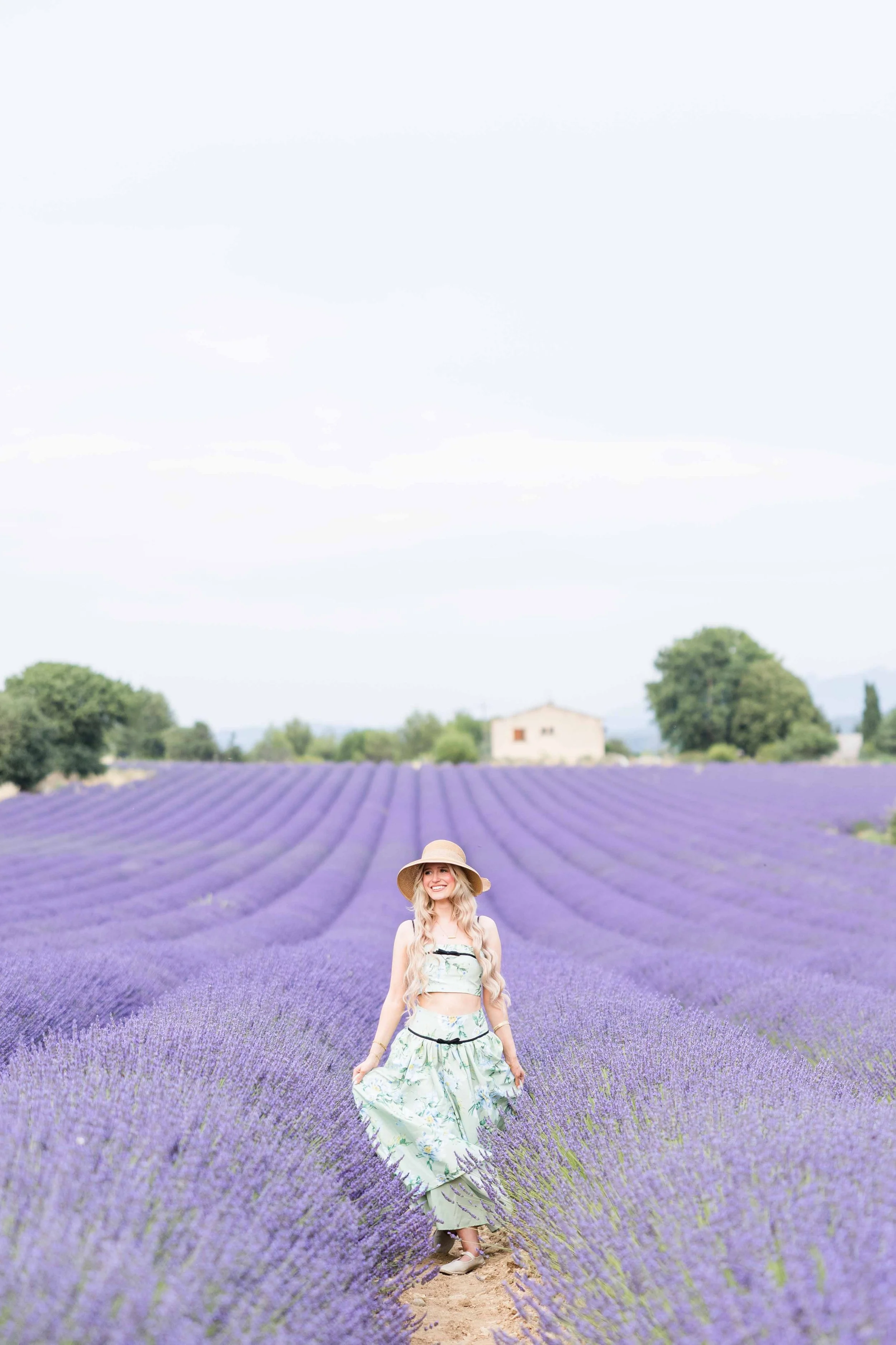  Wide portrait of a woman standing among endless lavender rows in Provence, France. 