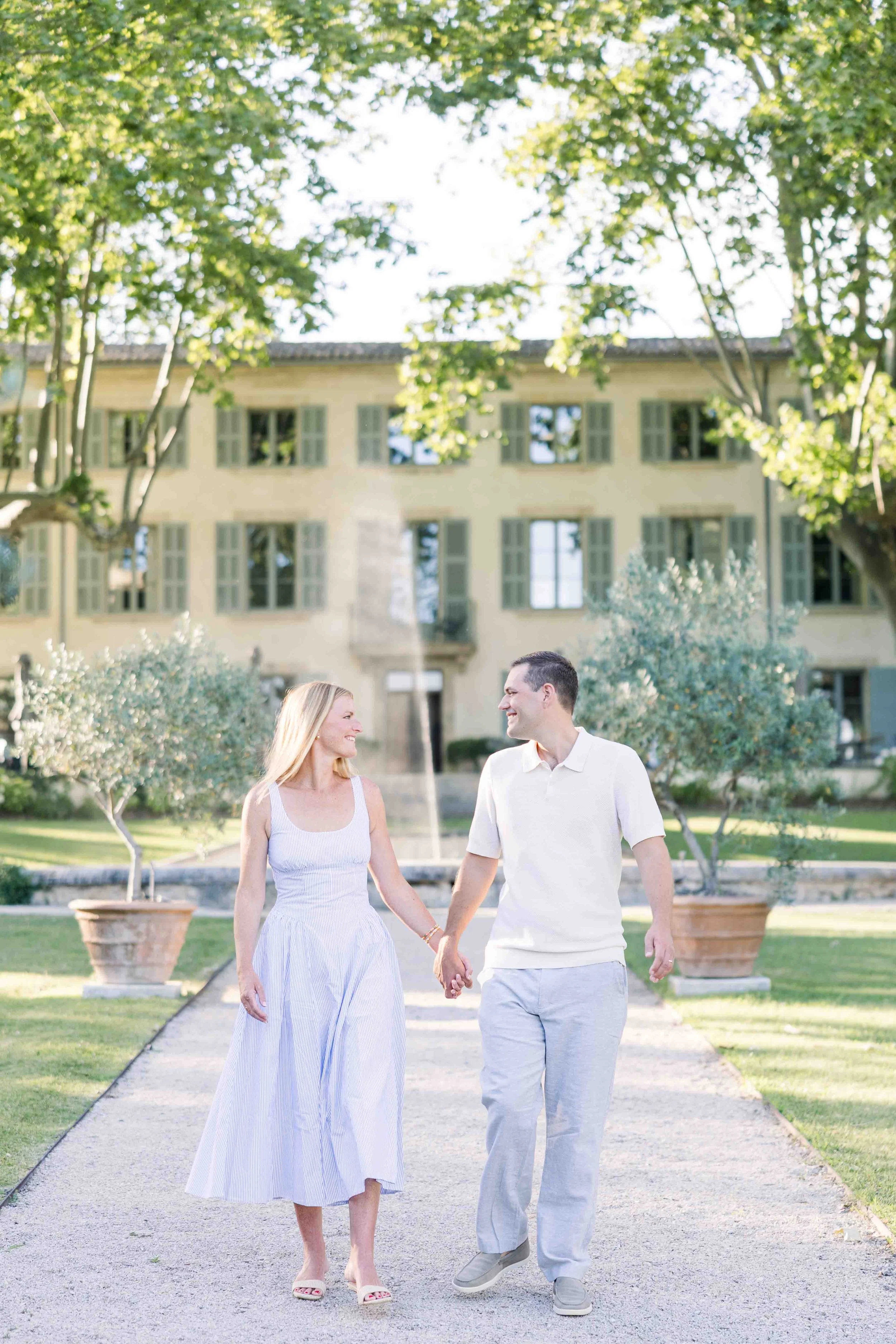 Couple walking together along a garden path with the Domaine de Fontenille estate in the background, Lauris, Provence
