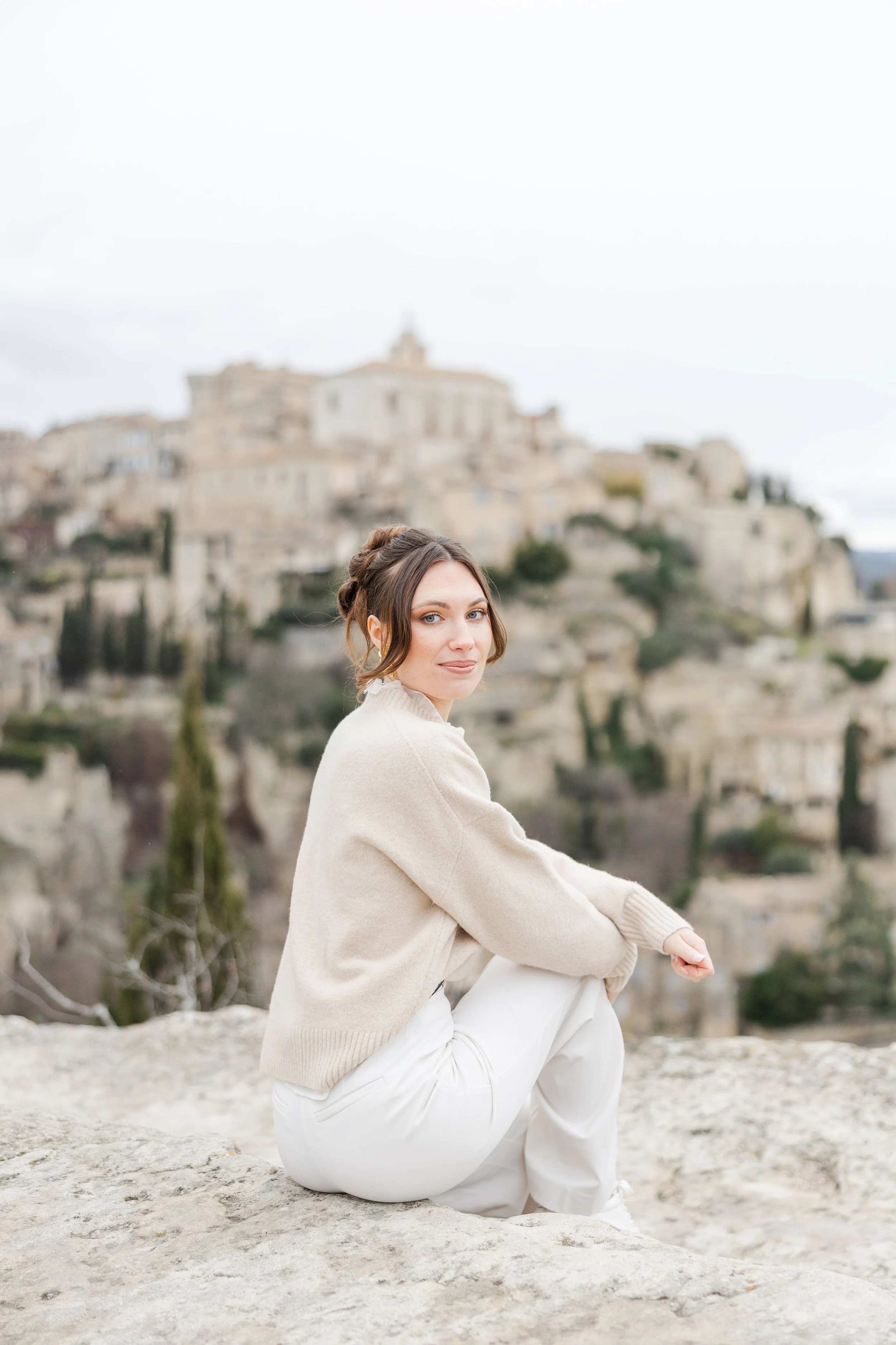Solo female lifestyle portrait in Gordes holding a lavender bouquet surrounded by warm golden Provence light