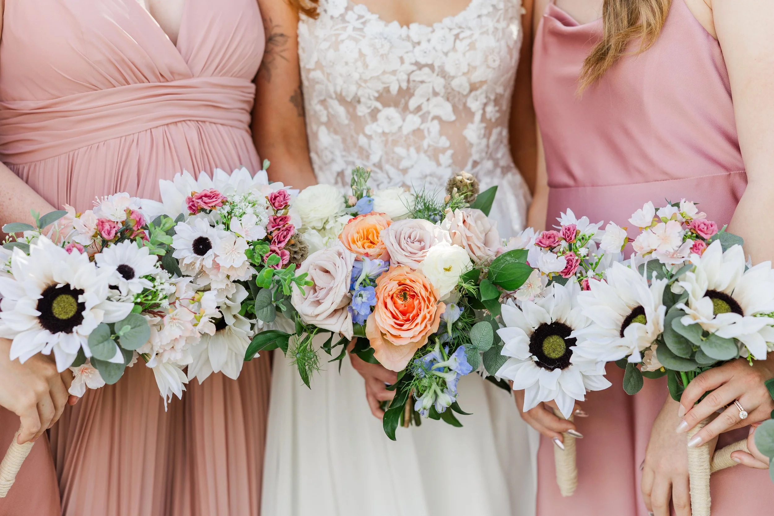 "Bridal party holding matching bouquets in coordinated dresses.