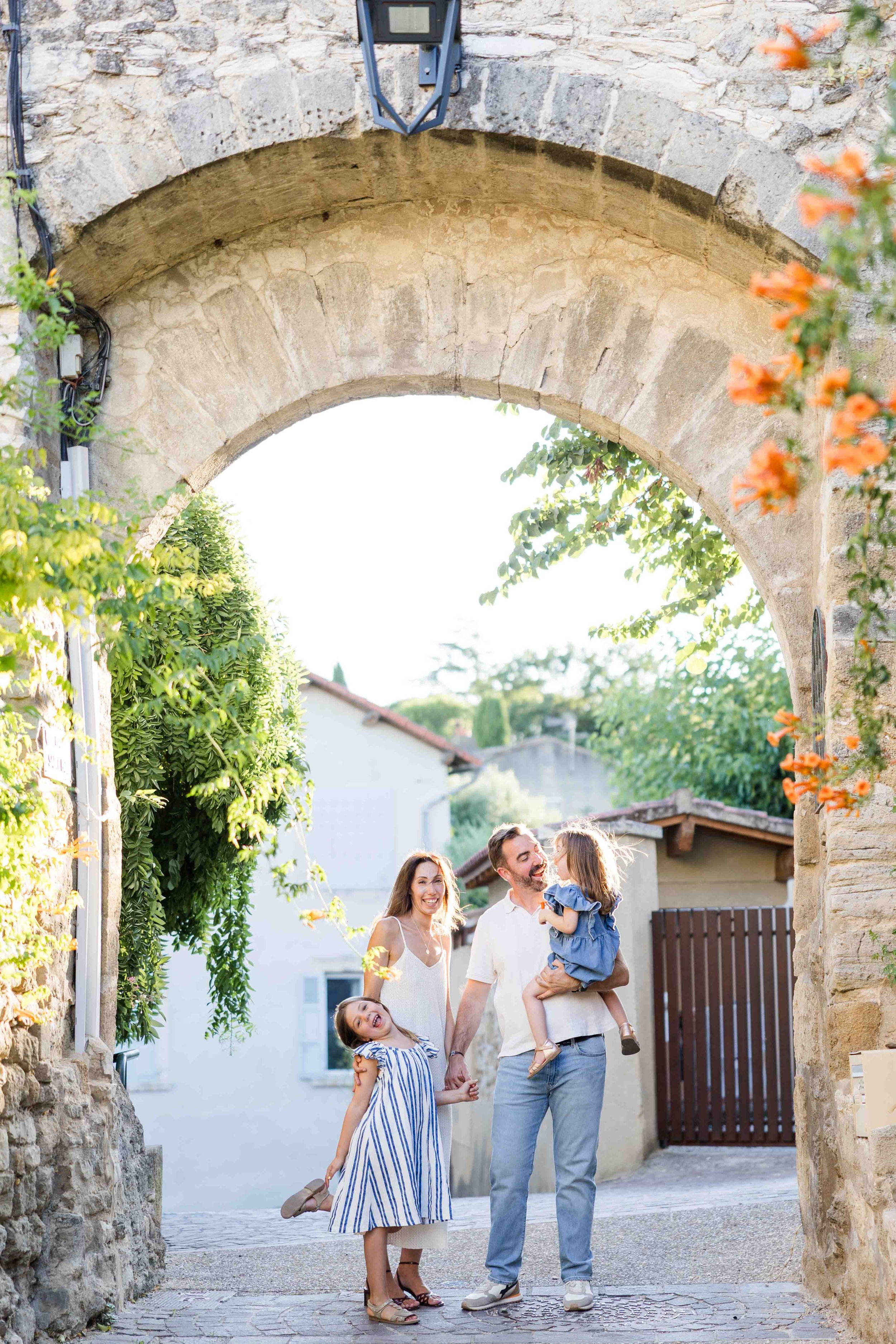 Parents laughing with their daughters during an authentic family photography session in Provence.