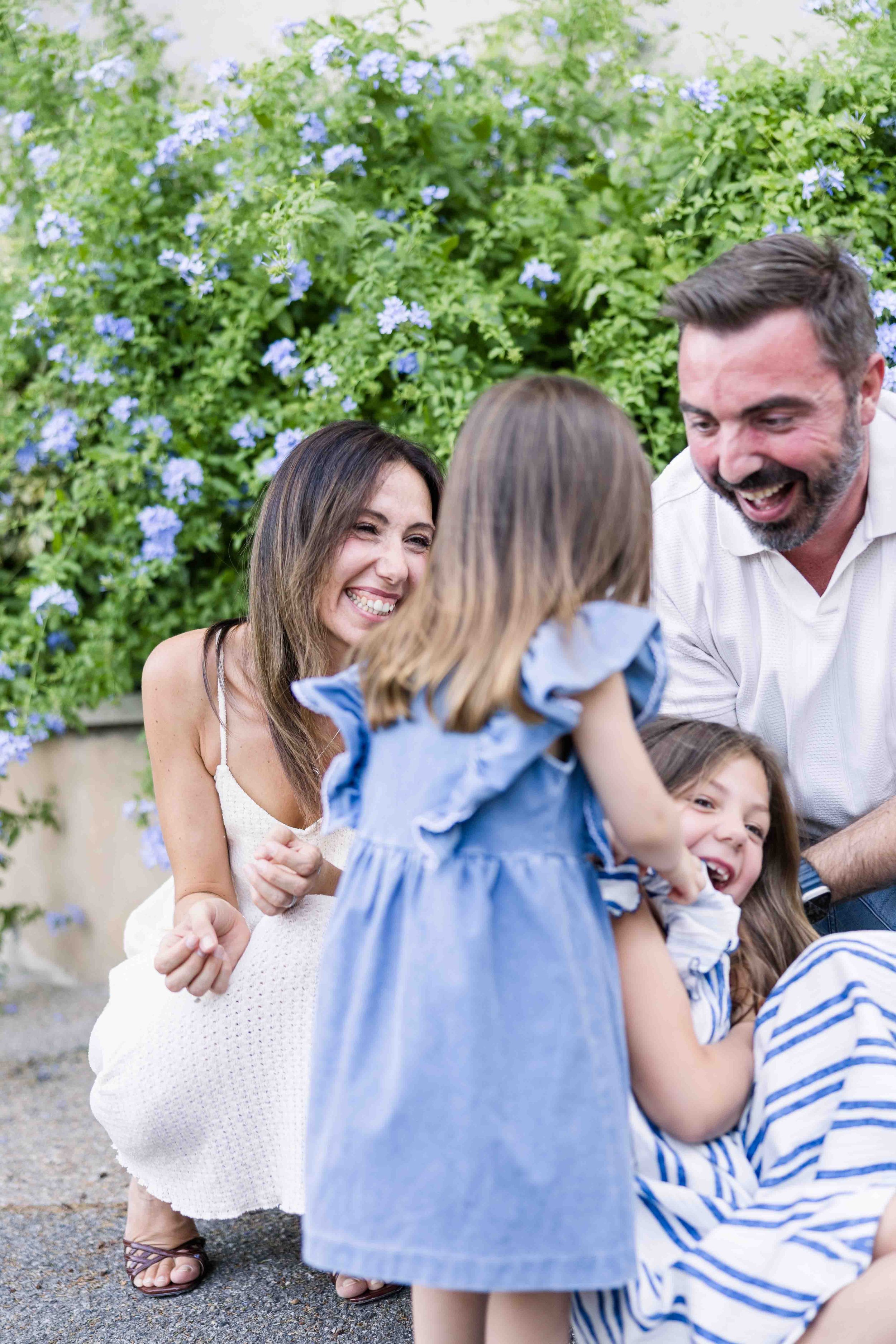 Parents playing and laughing with their daughters during a relaxed family photo session in a Provençal village.